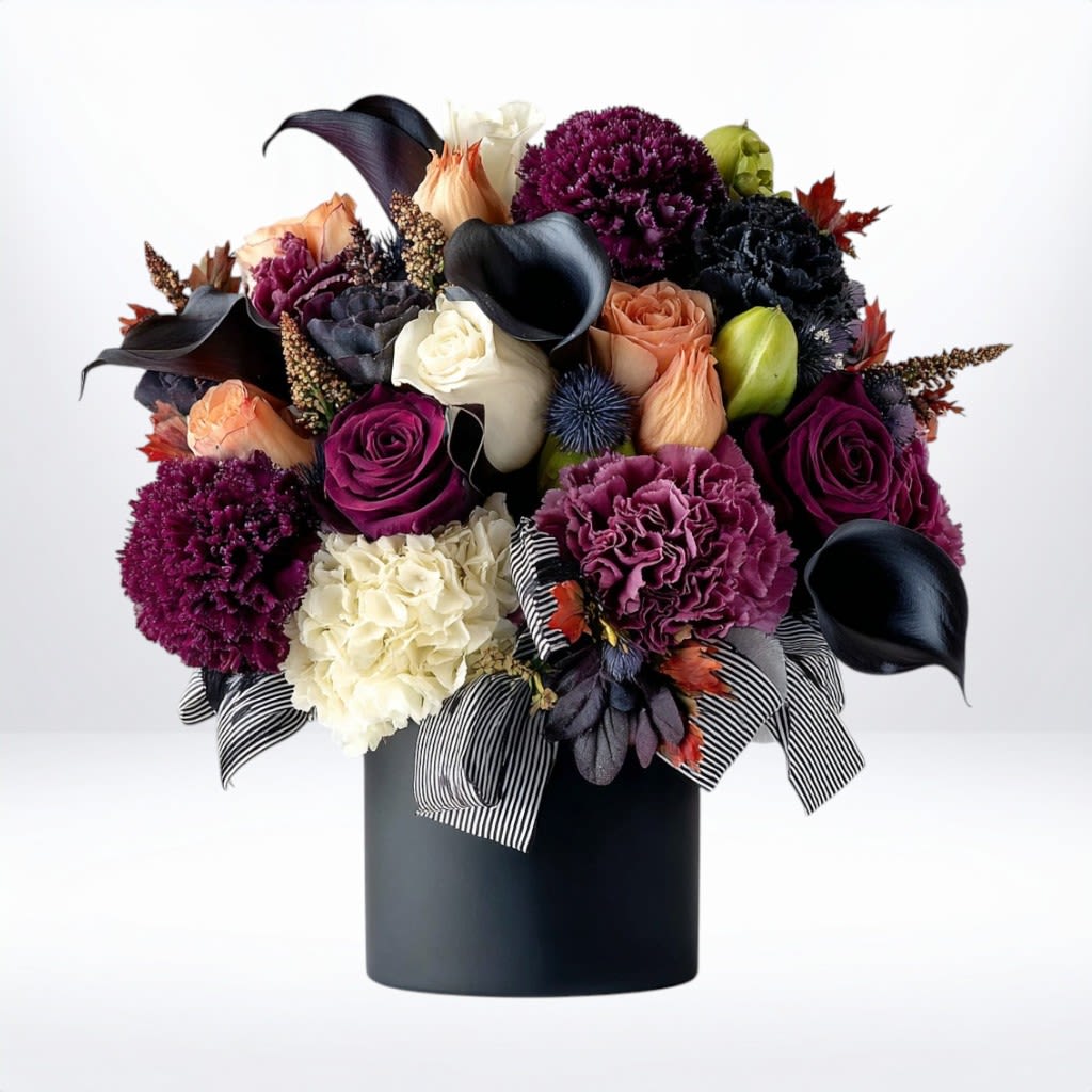 Nocturne Bouquet - The Nocturne Bouquet is a bold, artful composition that blends rich tones with modern elegance. Featuring deep plum carnations, striking black calla lilies, ivory and peach roses, and lush hydrangea, this bouquet is finished with moody foliage, textured pods, and a sleek striped ribbon for a contemporary touch. Designed in a modern black vase, it’s a captivating choice for birthdays, celebrations, thank-you gifts, or as a sophisticated centerpiece.  Available for same-day flower delivery in Galveston, Jamaica Beach, Tiki Island, Sea Isle, and surrounding coastal areas, this dramatic arrangement brings depth, style, and refined artistry to any occasion.  Substitution Disclaimer:  Due to seasonal availability, some blooms may be replaced with similar varieties of equal or greater value to maintain the design’s look and integrity. Your arrangement will always reflect the same spirit, palette, and premium quality.
