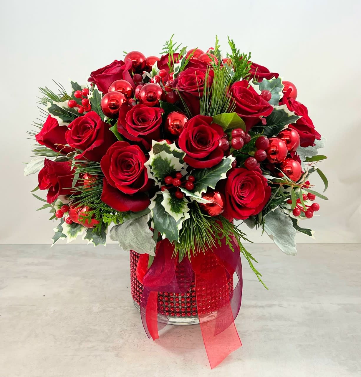 Holly Jolly Rose Bouquet - Classic Christmas elegance are words befitting to describe this beauty.  Sixteen stems of the finest red Christmas roses available, are artfully nestled in a bed of lush cedar and white pine that's full of holly to brighten the mood! Get ready for an over-the-top reaction when your friends and loved ones receive the Holly Jolly Rose bouquet.