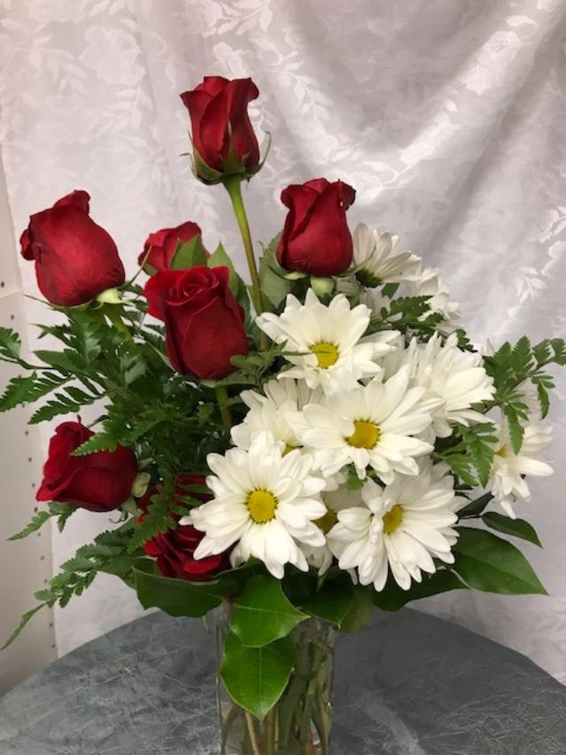 From Me!!! - This simple and beautiful arrangement grabs attention with the Red Roses partnered with White Daisies nestled on a bed of fern and other seasonal dark greenery. 
