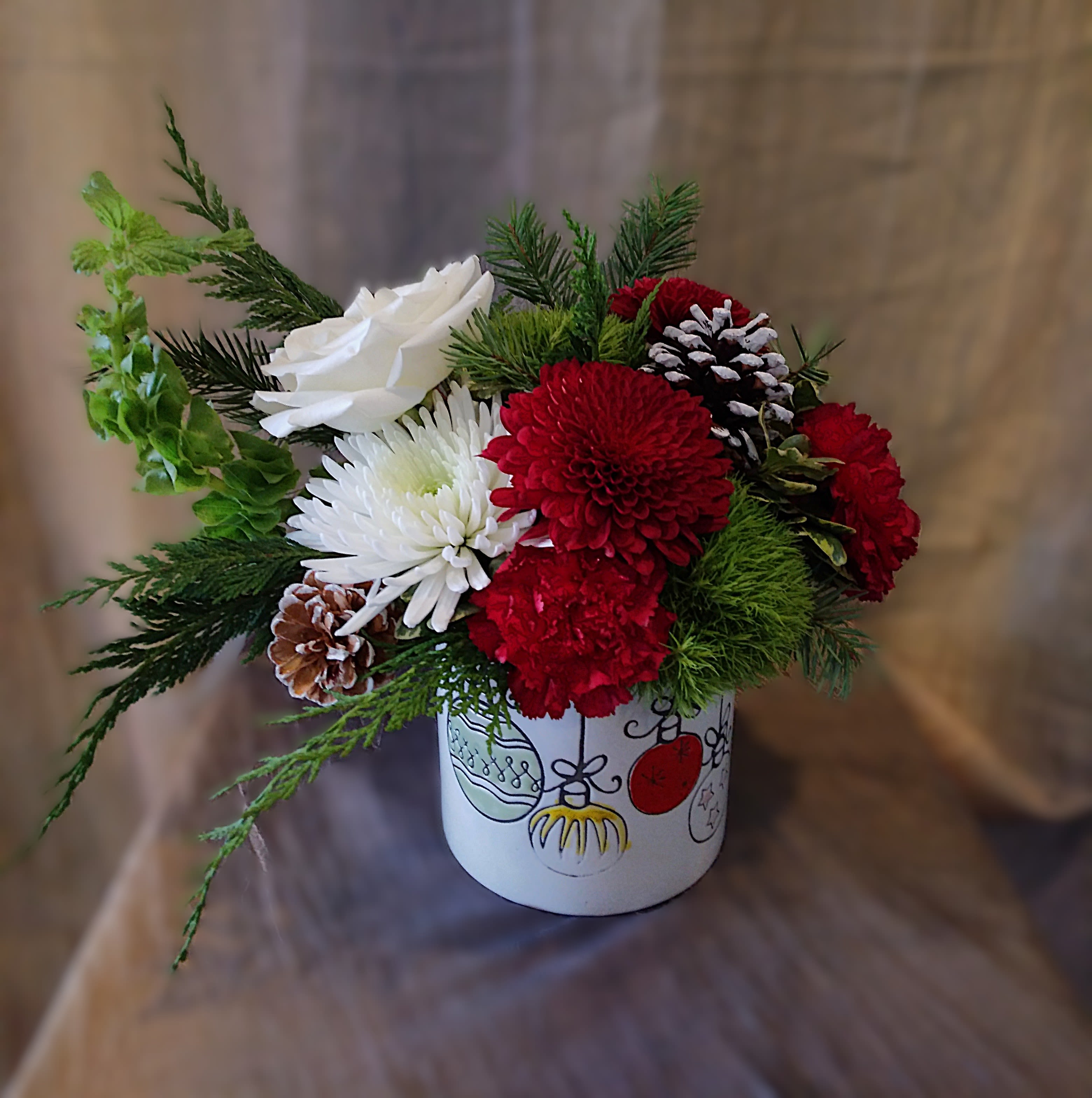 Holiday Hijinks - A playful mix of lush evergreens, festive blooms, and whimsical accents in white ceramic container — perfect for holiday mischief turned into cheer.