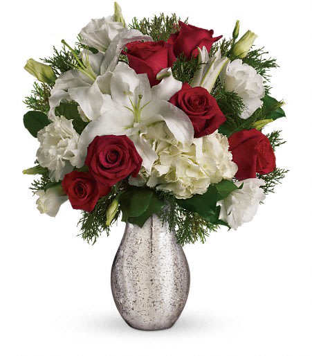 A Silver Kiss - Elegant, festive, and absolutely stunning — this arrangement blends rich red roses, snowy white lilies, and fluffy hydrangea in a chic silver mercury-glass vase. Winter evergreens add texture and fragrance, creating the perfect balance of modern style and timeless holiday charm. A gorgeous choice for Christmas celebrations, winter birthdays, or as a gift that instantly elevates any space. *Shown as deluxe*