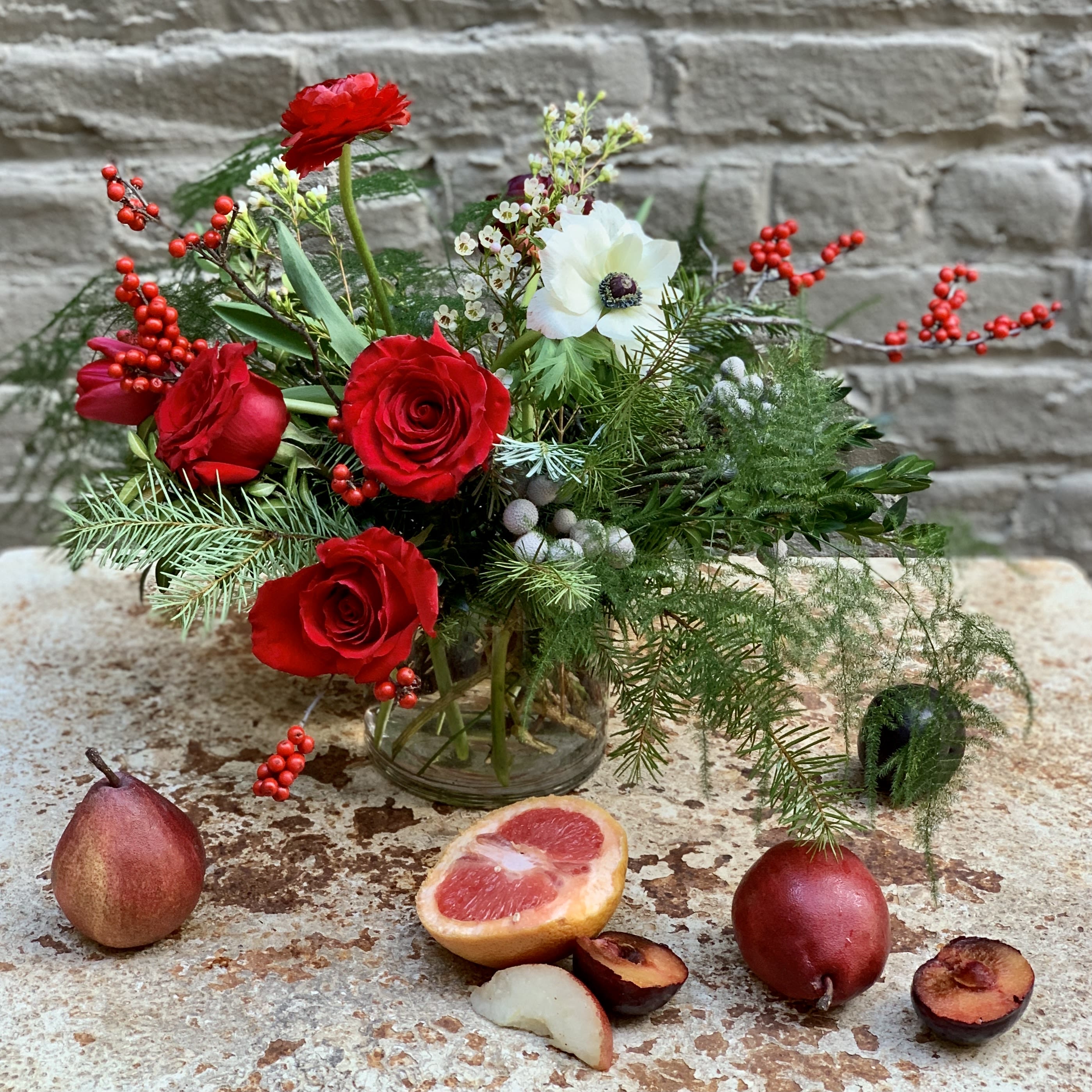 Season's Greetings - Bounties of evergreens, berries, and blooms make this lovely arrangement the perfect way to express festive cheer for the season!  Makes a wonderful centerpiece (or host gift) for your next holiday shindig.    Fresh cut fruit is not included, but feel free to use our photo as inspiration for your own holiday tablescapes.  Arrangement measures approximately 12x12&quot;.