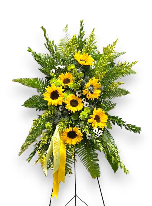  Sunshine Cascade Easel - This stunning arrangement features a vibrant display of golden sunflowers artfully arranged among lush greenery and delicate accent blooms. The sunflowers’ cheerful faces burst forth in a delightful cascade, symbolizing warmth, adoration, and lasting remembrance. Finished with a graceful yellow ribbon, the Sunflower Cascade Easel brings a touch of sunshine and hope to memorial services, celebrations of life, or any occasion that calls for a heartfelt floral tribute.