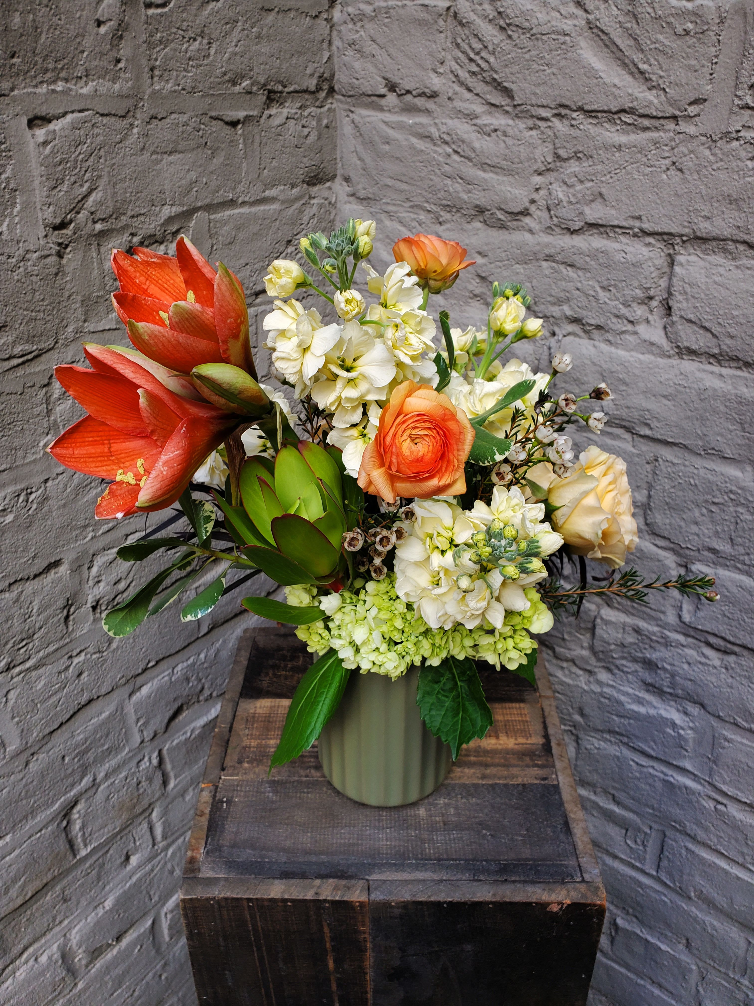 Amaryllis Sunrise - Looking for a splash of color to warm up your winter?  This beautiful arrangement of sunrise-hued blooms -- including a stunning and vibrant amaryllis -- might be just the ticket.  Amaryllis, stock, ranunculus and more nestle in a 6&quot; tall ceramic green vase.  Standard arrangement measures approximately 13&quot; tall by 9&quot; wide.
