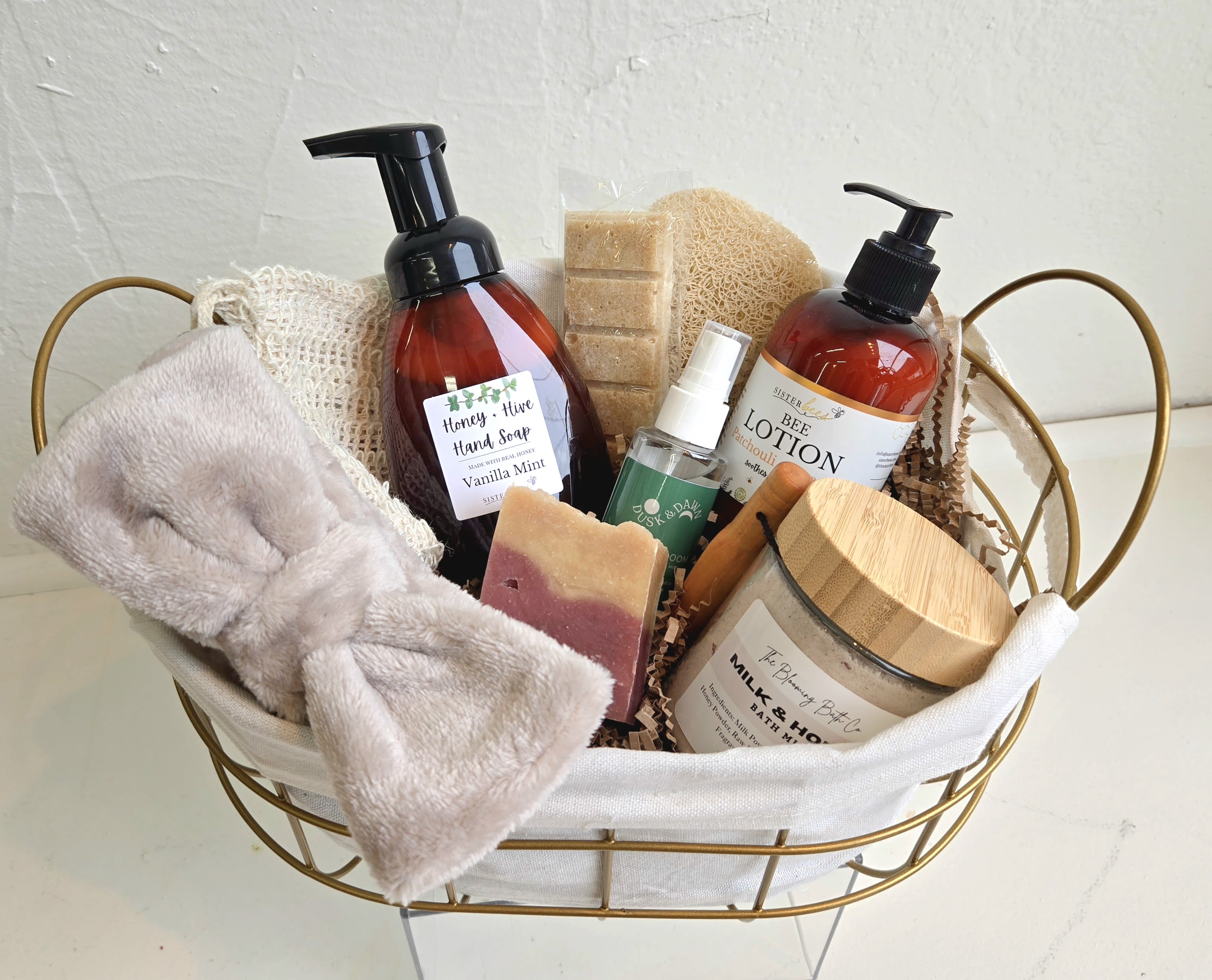 Spa Gift Basket #1 - Our curated spa basket includes a soft taupe bow headband, desert bloom hydrating facial mist, sister bees' lotion patchouli &amp; orange, handcrafted blooming bath co milk &amp; honey bath milk, a beautiful bar of soap, handcrafted soap sugar scrub (oatmeal, honey &amp; sugar), loofah sponge, a bar saver bag, as well as a large hand soap by Sister Bees in a vanilla mint.