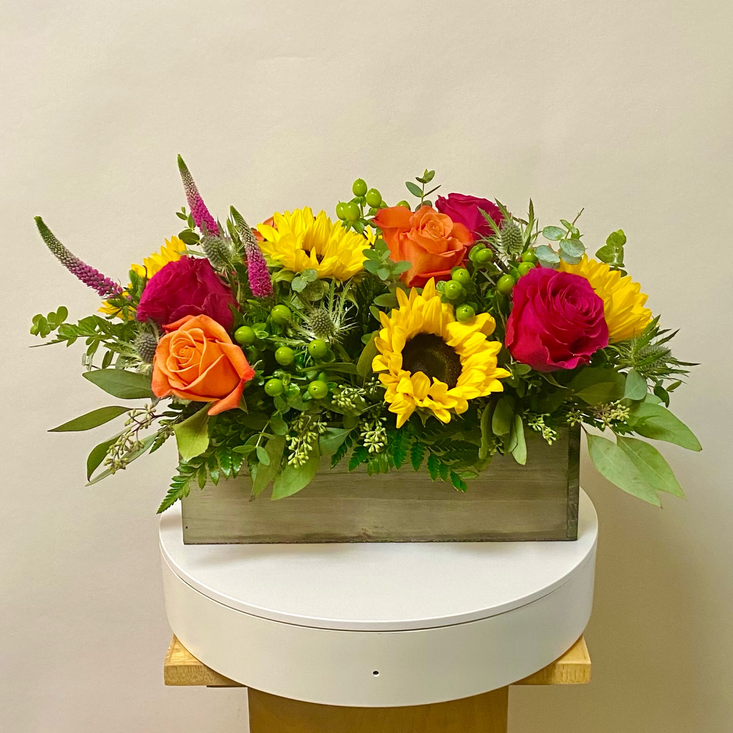 Rustic Charm - This Wooden Box Arrangement includes Sunflowers, Hot pink Roses, Orange Roses, Green Hypericum Berries, Blue Thistle and Hot pink or Purple Veronica. Or as Similar as Possible. 