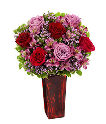 Love's Promise - A promise that can be kept by giving this beautiful arrangement of Red &amp; Lavender Roses with pink alstromeria and pink wax flowers nestled in a bed of greenery and arranged in a tall square red vase. 