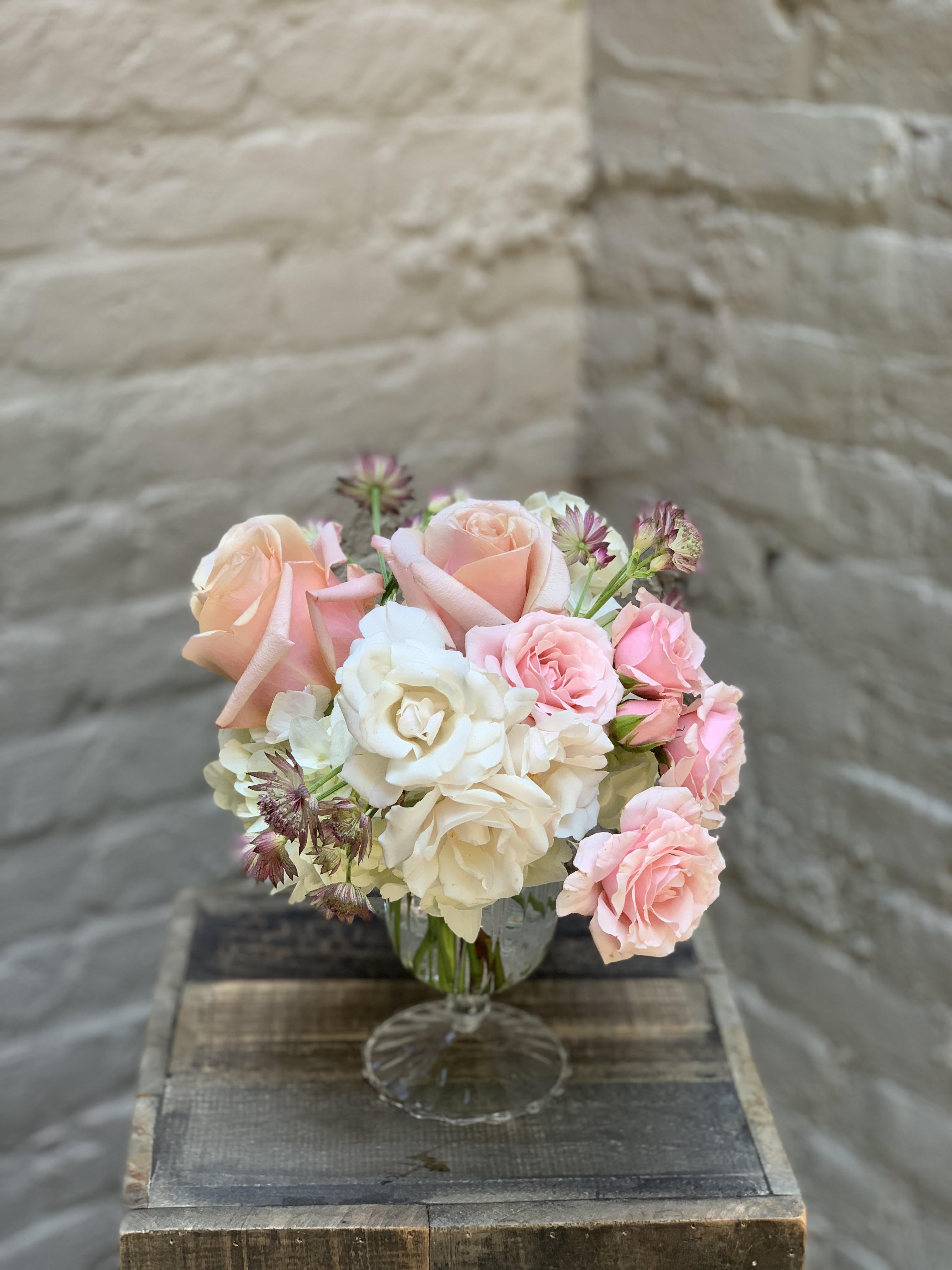 Edelweiss - Soft and dreamy clouds of white hydrangea, roses, and astrantia in an elegant glass compote.  Glass compote measures 6"x3".