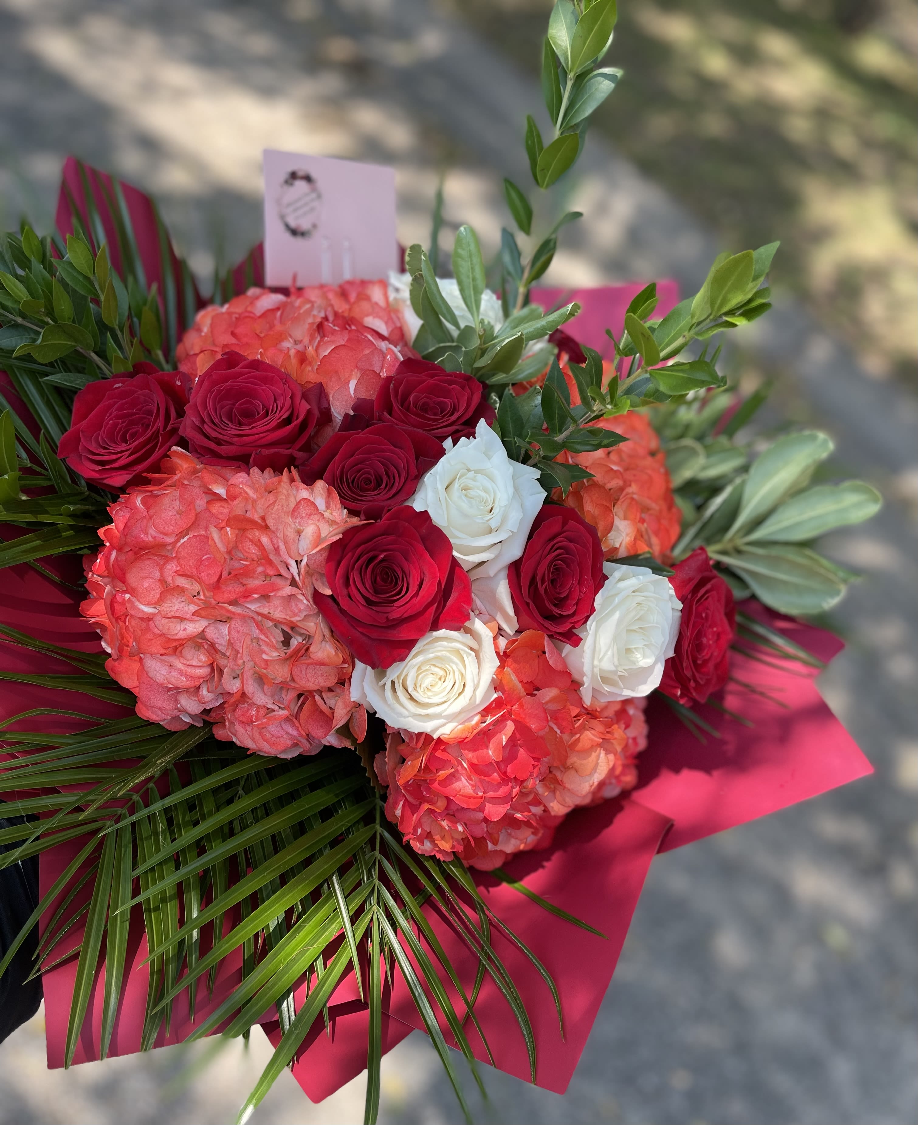 For You Wrapped Bouquet  - 7 red roses 5 white roses and three red/orange hydrangeas with palm and greenery wrapped in paper.    In some instances, our photo may represent an overall theme or look and include a one-of-a-kind vase which cannot be exactly replicated.  Although the actual bouquet may not precisely match the photo, its temperament will. Occasionally, substitutions of flowers and/or containers happen due to weather, seasonality and market conditions which may affect availability. If this is the case with the gift you’ve selected, we will ensure that the style, theme and color scheme of your arrangement is preserved and will only substitute items of equal value or higher value.  If any design elements are of major importance to your order, please include them in the florist instructions at checkout or contact us to ensure availability.