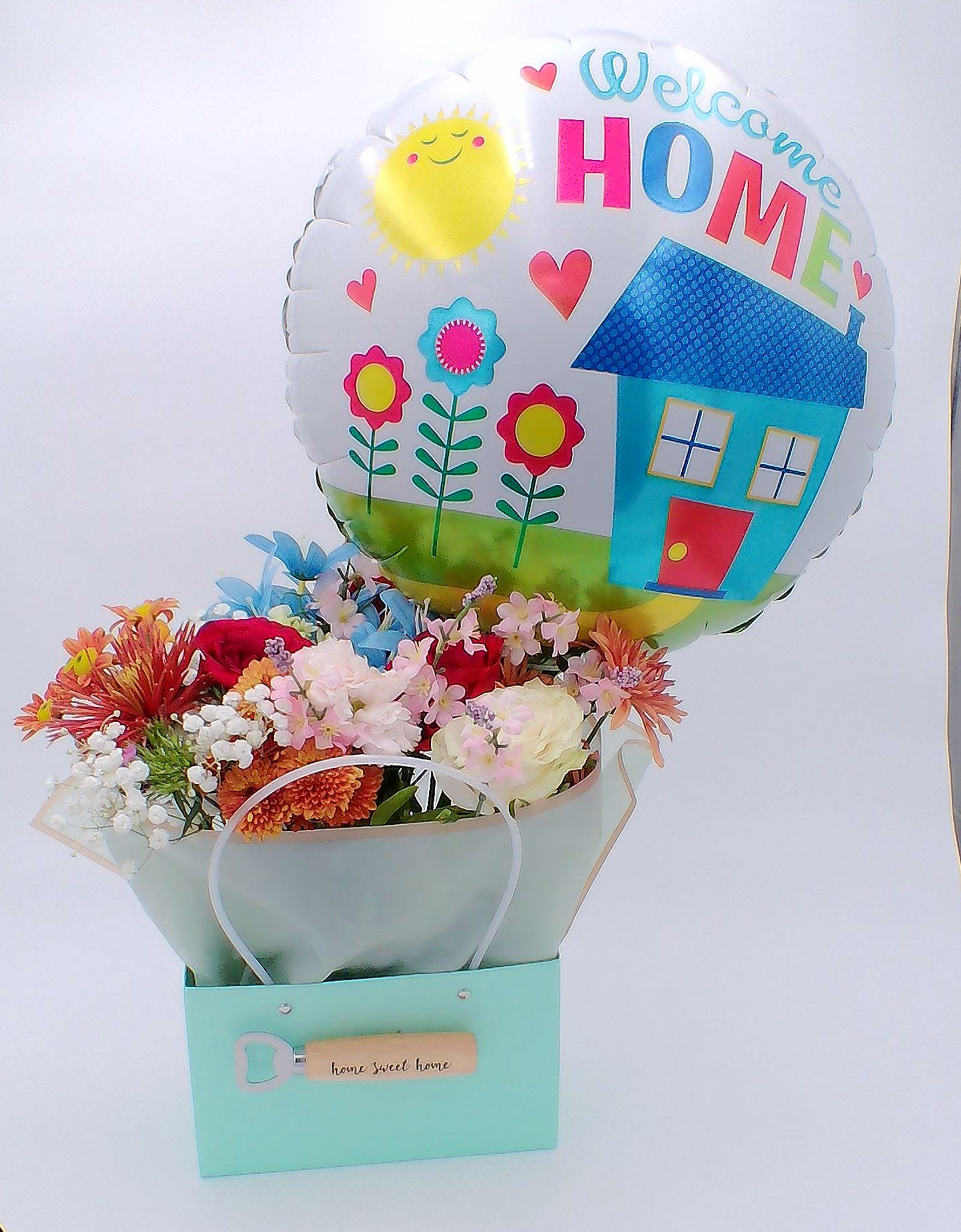 &quot;Welcome Home&quot; Flower Gift Bag with Balloon - Mixed Fresh Flowers (14–16 stems): warm and cheerful blend of 6 carnations, 4 daisies, 2 roses, 2 baby breath,2 chrysanthemums, welcoming colors to brighten any homecoming. 18-inch “Welcome Home” Foil Balloon (1 pc)  &quot;Home Sweet Home&quot; wooden bottle opener (1pc) Reusable Gift Bag (32.5 cm × 22 cm × 13 cm) (1pc) Total Weight: Approximately 700 g Ideal for: Homecoming celebrations, surprise welcome-back gifts, hospital return visits, new home arrivals, and thoughtful gestures for family, friends, or loved ones returning after travel or time away.