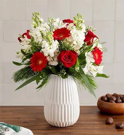 Dazzling Christmas™ Bouquet - Celebrate the most magical time of year with our dazzling bouquet. A rich gathering of blooms in classic red and white is accented by lush greenery. Hand-designed in our keepsake White Modern Vase, featuring a tapered design and matte finish, it’s a gift that brings the joy of Christmas to family and friends, near and far. -Arrangement with red roses and mini Gerbera daisies, white stock, Peruvian lilies (alstroemeria) and Limonium; accented with feather willow eucalyptus and assorted Christmas greenery --Artistically designed in our Modern White Vase, with a tapered design and a matte finish, for a contemporary look that also has a softness to it, to complement everyday arrangements; measures 8&quot;H x 5.35&quot;L x 5.35&quot;W -Large arrangement measures approximately 20&quot;H x 16&quot;W  -Medium arrangement measures approximately 19&quot;H x 15&quot;W  -Small arrangement measures approximately 18&quot;H x 14&quot;W  Our florists hand-design each arrangement, so colors and varieties may vary due to local availability To ensure lasting beauty, Peruvian lilies may arrive in bud form and will fully bloom over the next few days-