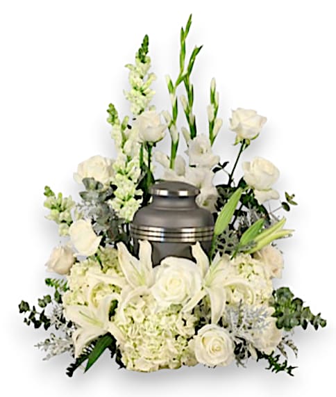 Eternal Peace Urn  - This stunning casket saddle is a heartfelt tribute that beautifully honors the memory of a loved one. Adorned with lush foliage of silver dollar eucalyptus, dusty miller, and sword fern, it exudes a graceful elegance. The arrangement features three stunning white hydrangeas, their large blooms symbolizing heartfelt sincerity, alongside three graceful white gladiolus, which represent strength and moral integrity. A striking display of ten pristine white roses conveys deep love and respect, while three delicate white snapdragons add a touch of graceful beauty. Completing the arrangement, two elegant stems of white lilies embody purity and renewal. Together, these flowers create a serene and comforting composition, offering solace to family and friends during this poignant time.   (Urn not included.)