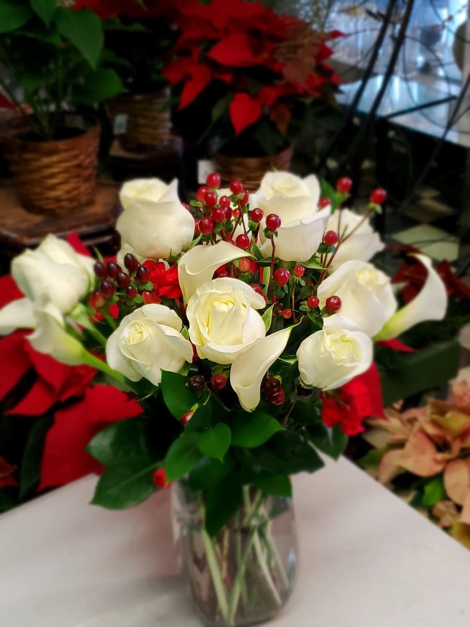 Christmas Elegance - Crystal White Mini Callas, White Roses and Red Hypericum with Fragrant Evergreens in a vase is sure to add a Touch of Elegance to any decor