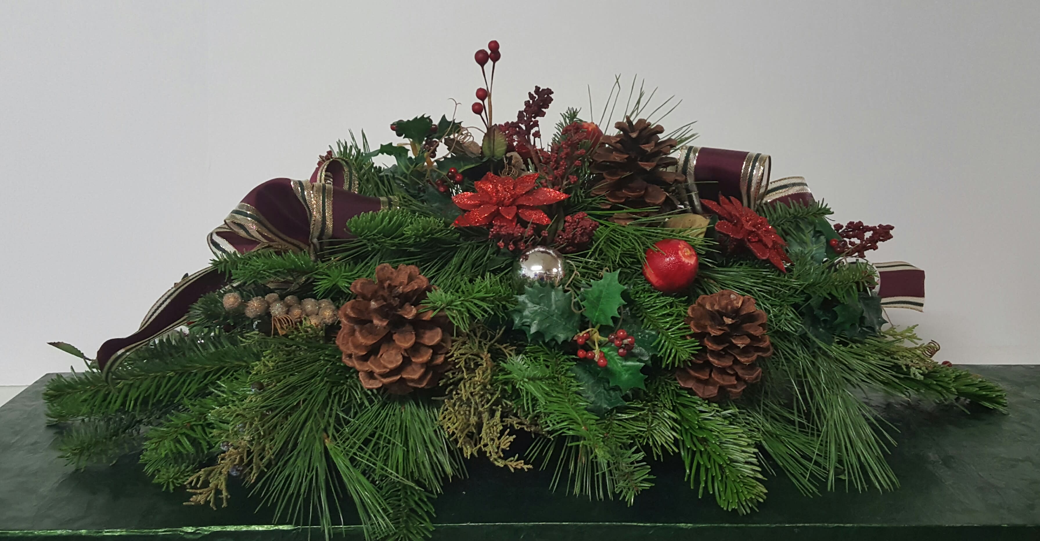 Designer's Choice Holiday Centerpiece - Holiday fragrance and beauty all in one package. This holiday centerpiece is created with various winter evergreens and adorned with berries and other seasonal ornamentation. Illuminate your table with added candles, or just enjoy the natural beauty of a Christmas classic.