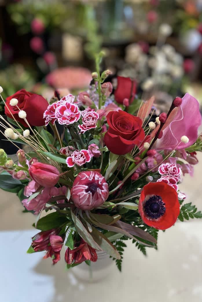 Crimson Lights - This beautiful grouping of red flowers is exciting, unique, vivid and full of movement.  Concentrated color, unusual flowers and skill all combine in an earthy ceramic grey vase.  