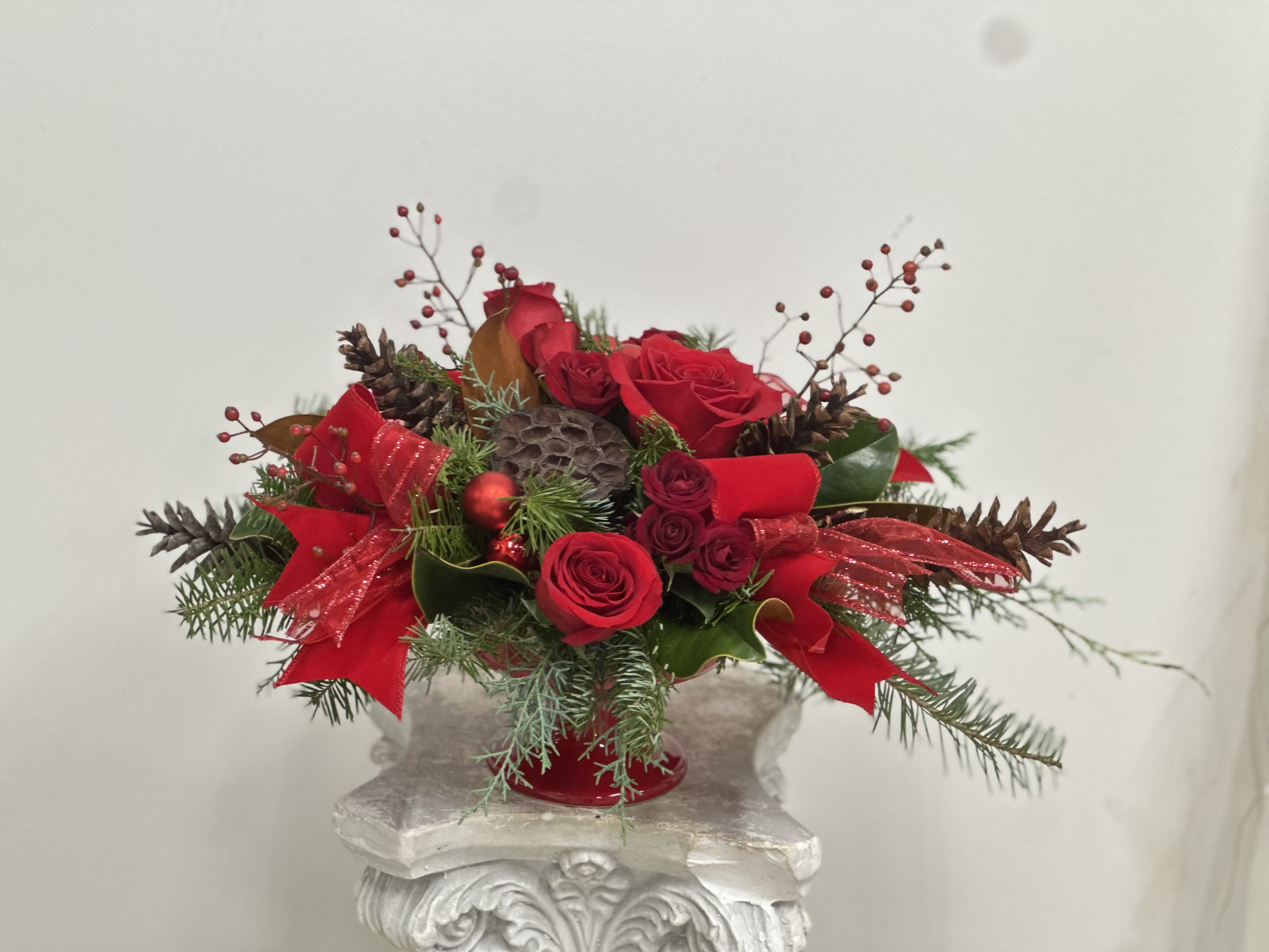 Red Elegance by Westford Florist Art by Veny - Elevate your holiday gatherings with the exquisite &quot;Red Elegance&quot; luxury arrangement by Westford Florist Art by Veny. This stunning centerpiece features rich red roses and delicate spray roses, beautifully complemented by vibrant berries and adorned with a luxurious velvet ribbon infused with subtle sparkle. Accents of shimmering ornaments, dry lotus pods, and natural pinecones enhance the festive charm, all nestled among a lush mixture of Christmas greens in an elegant ceramic pot. Transform your celebrations into unforgettable moments as this sophisticated piece embodies the spirit of harmony and joy throughout the season. Make every gathering memorable with &quot;Red Elegance&quot; — where beauty meets sophistication.