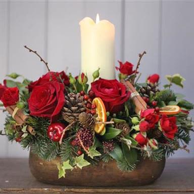 Noel By Black Cat Florist  - This centerpiece is a classic and elegant design perfect for the holiday season, evoking warmth, tradition, and cheer.  This arrangement is designed to be viewed from all sides and would make a stunning feature on a dining table or mantlepiece during the winter holidays.  *Battery operated LED candles 