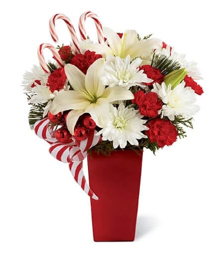 Candy Cane Holidays - Bursts with the bright cheer and jubilant beauty of this special season Candy Cane Holidays celebrates the joy and beauty of the holiday season with a candy-cane themed presentation that will sweeten anyone's day! Brilliant white Asiatic lilies and chrysanthemums are arranged with red mini carnations to mimic candy cane colors for a beautiful and festive look.   Red glass balls, holiday greens, a festive candy-striped ribbon, and three candy canes create the perfect finishing touch. Presented in a red ceramic vase, the arrangement is a splendid way to send your Christmas wishes to someone special this season.  Due to availability, the vase that arrives with your flowers may be different than the one shown on our website photography.