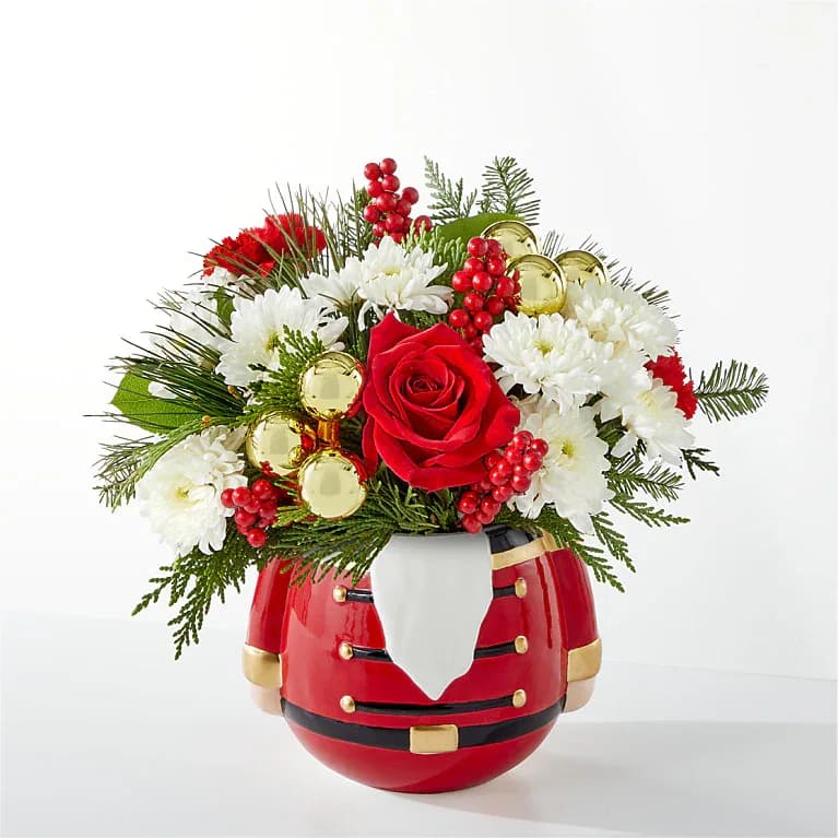 Magical Merry Nutcracker - Share in the nostalgia of the season with a collectable nutcracker vase perfectly accented with holiday blooms. Blooms included are red roses, red carnations, accent berries, decorative mini gold ornaments and fresh christmas greens. For long–lasting blooms, replace the water daily. We suggest trimming the stems every couple days.  Please note the bouquet pictured reflects our original design.  If the exact flowers or container in this arrangement are not available, we will sub for the freshest available flowers equal to or greater in value and closest available container.