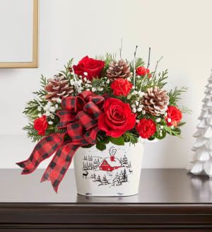 Countryside Christmas Tin - Our rustic-style bouquet is a wonderful way to celebrate the season. Red &amp; white blooms are gathered with lush greens, snowy-tipped pinecones, birch accents and a charming plaid ribbon. All-around arrangement with red roses and mini carnations; accented with baby’s breath, white birch, assorted Christmas greenery and snow-tipped pinecones picks.  It’s a gift that brings the quiet enchantment of winter to loved ones near and far. Artistically designed in our keepsake Countryside Christmas Tin, an oval-shaped canister adorned with a quaint village scene inspired by the quiet enchantment of a winter’s day; designed with a milk-washed finish and twin handles.   Please note the bouquet pictured reflects our original design.  If the exact flowers or container in this arrangement are not available, we will sub them for the freshest available flowers and closest available container.