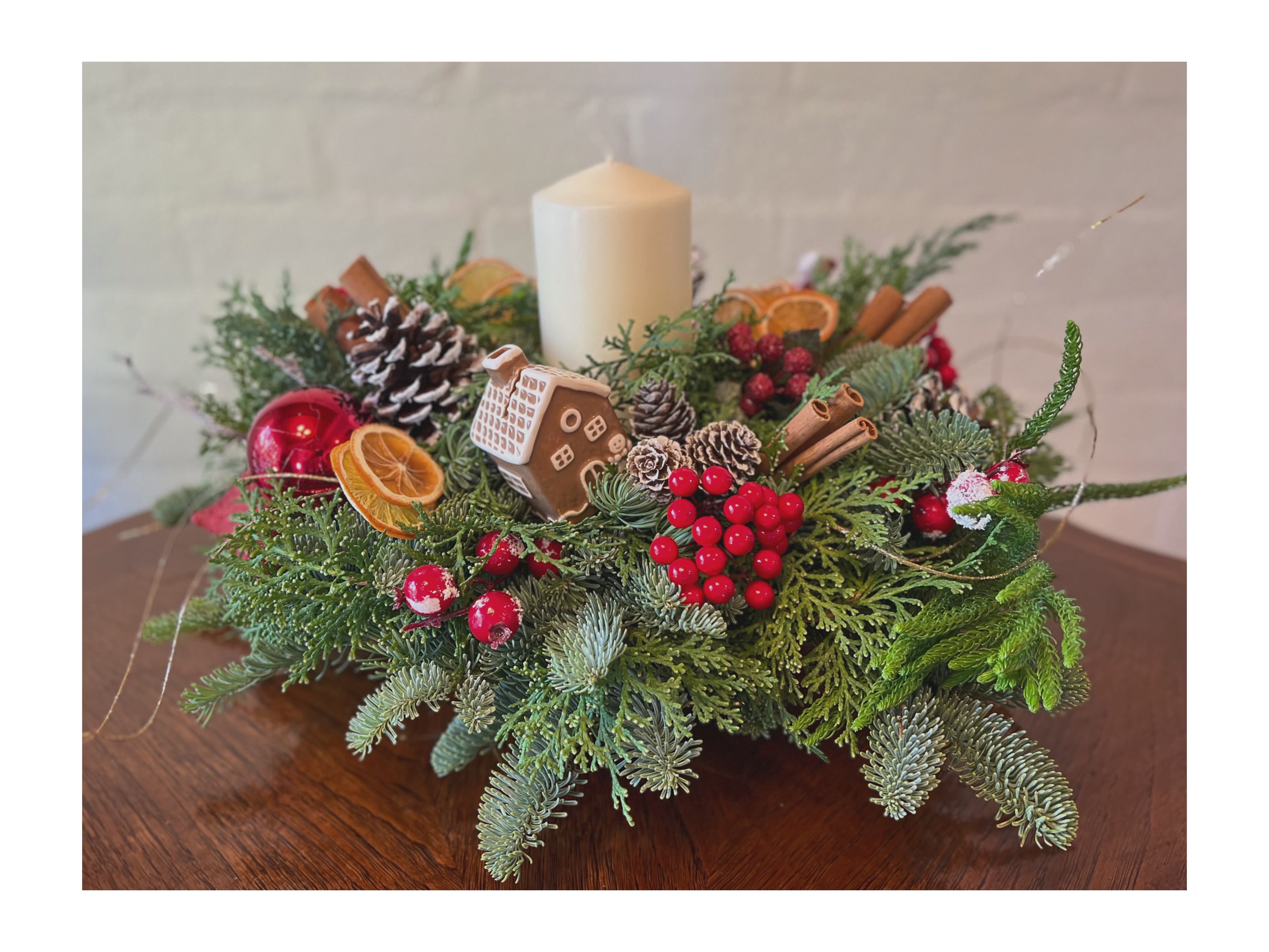 Round Centerpiece w/ candle- red &amp; white - Crafted with seasonal foliage, dried oranges, pine cones &amp; cinnamon. Red and white accents and ornaments.