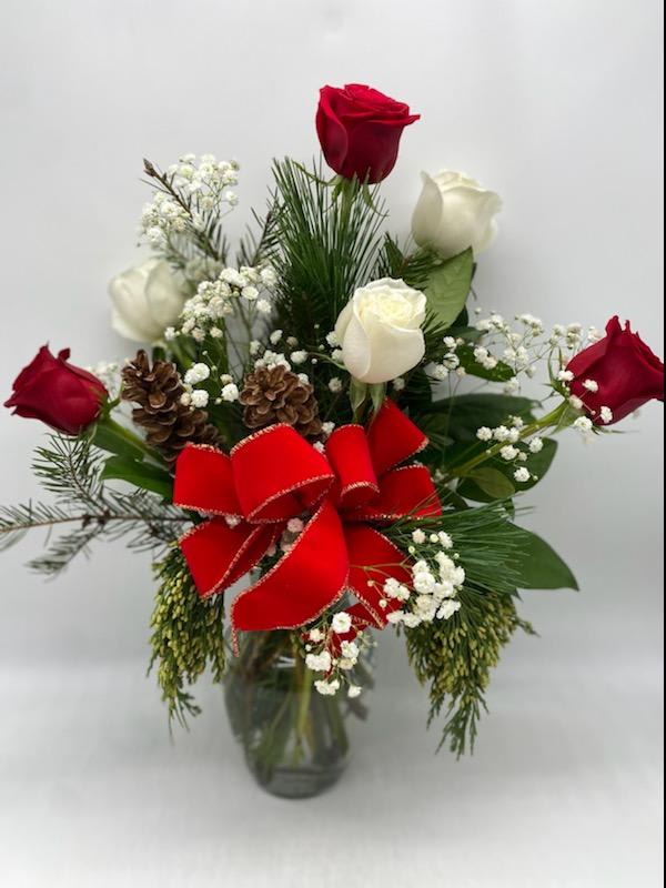 The Winter Rose Mix - A clear vase of red &amp; white roses mixed amongst Christmas Greens and a Hand crafted bow