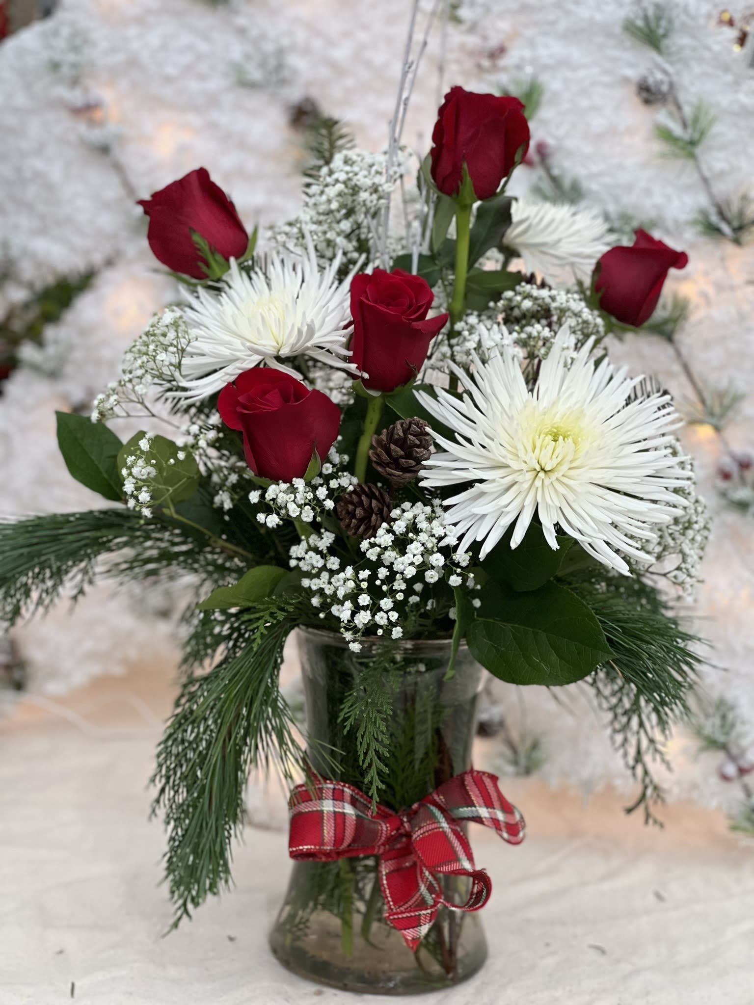 Winter Wishes - A Holiday Mix, with Roses, Fresh Greens, and Festive Flowers. Arranged in a tall vase, Winter Wishes is an arrangement that gives you the chance to send your Holiday Wishes!