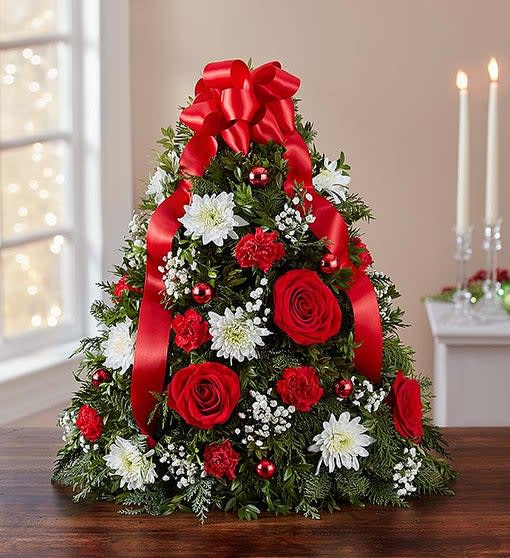 Christmas Flower Tree  - This flower tree arrangement is popular for its festive style and compact size at 14 inches, which fits perfectly into any space. Hand-designed with fragrant evergreens, then trimmed with ornaments and a red bow on top, this floral twist on a traditional tree makes a original gift for family, friends, or your own home.