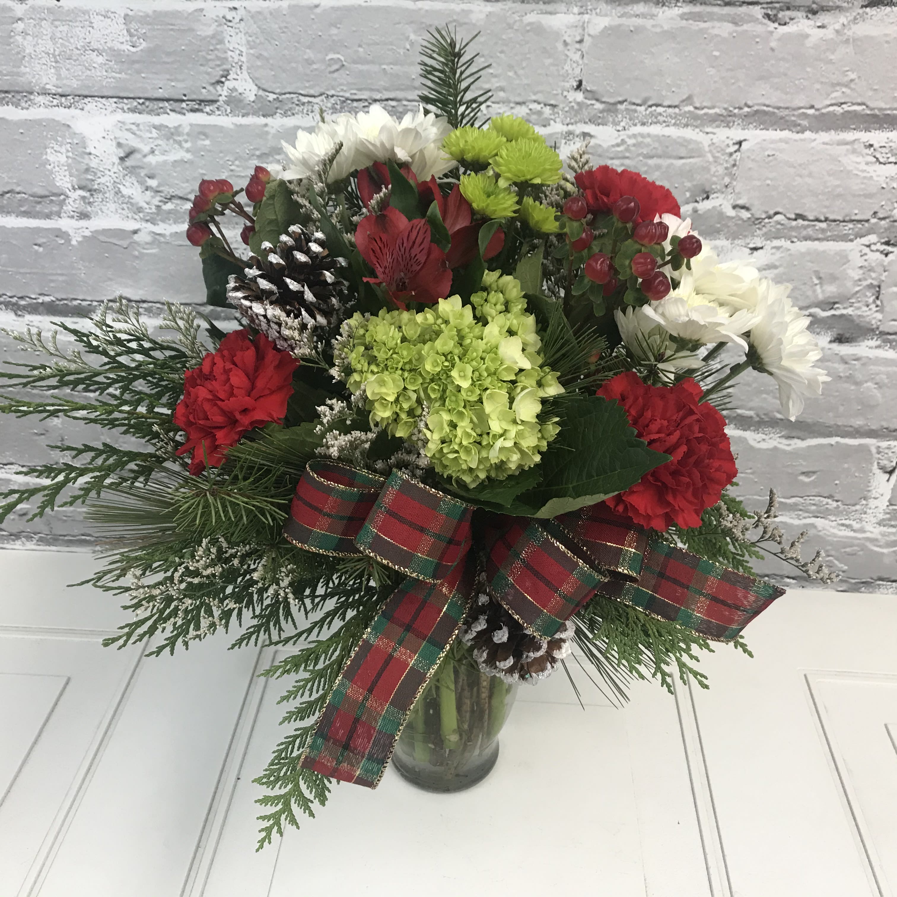 Holiday Designer Choice - Designer choice with a holiday focus. This item will not be exactly like the picture. The picture is for reference only. Holiday arrangement with reds, whites, greens, and evergreens included too!