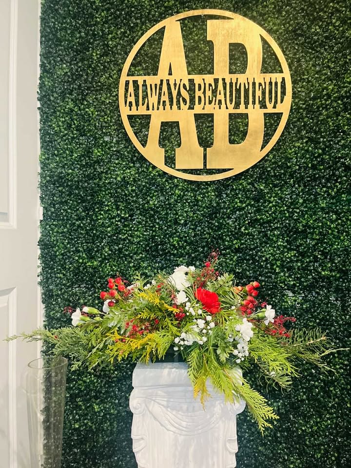 Christmas Centerpiece Decorated - This Christmas centerpiece is a lush and elegant arrangement crafted entirely from vibrant Christmas greens, beautifully adorned with festive flowers. A rich mix of fragrant evergreen branches, including pine, fir, and spruce, creates a full, textured base, evoking the spirit of a winter forest. Sprigs of holly with their glossy, spiked leaves add a touch of festive contrast, while the deep green of boxwood enhances the centerpiece’s refined look. Subtle sprigs of cedar lend a soft, feathery texture, while seasonal blooms, such as red poinsettias, white lilies, and delicate roses, bring vibrant color and a touch of holiday cheer. This centerpiece combines the beauty of fresh greens and the charm of seasonal flowers, creating a stunning and joyful addition to your holiday table.