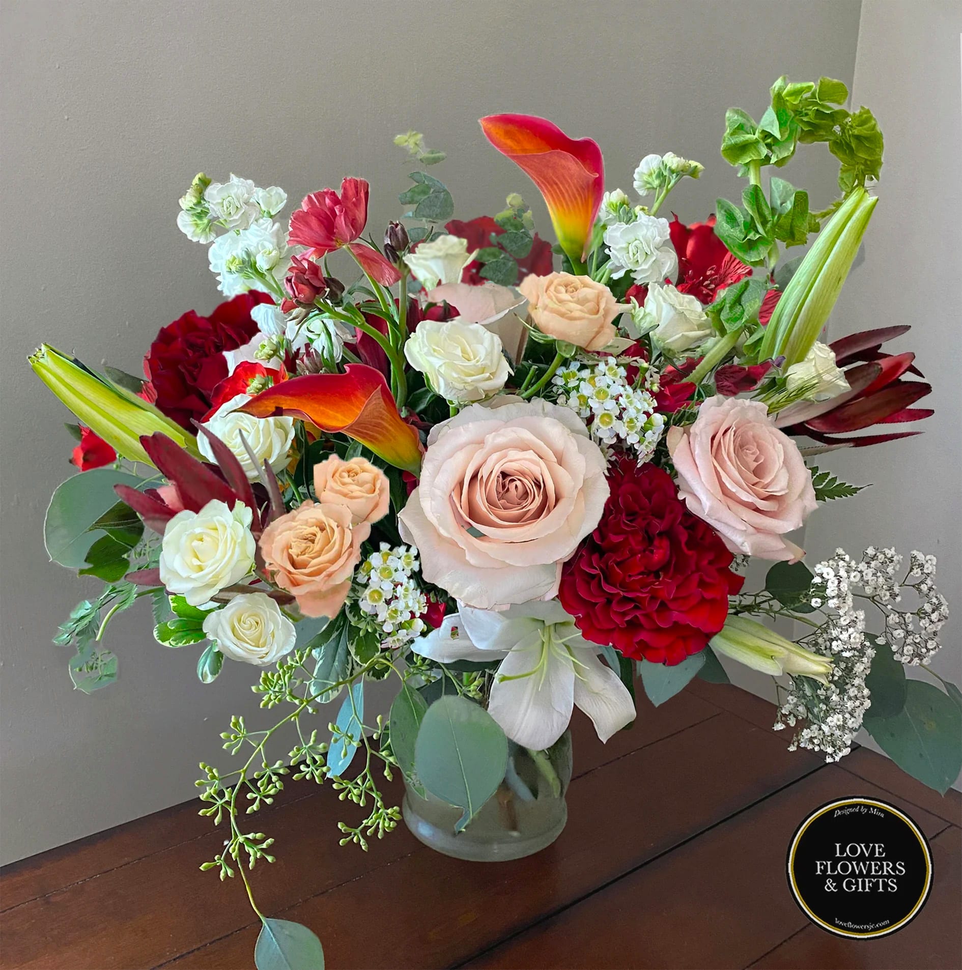Crimson Creme  - An elegant and light autumn arrangement made of a mix of creams and reds with fresh greenery designed in a glass vase. Perfect for the romantic occasion in the season