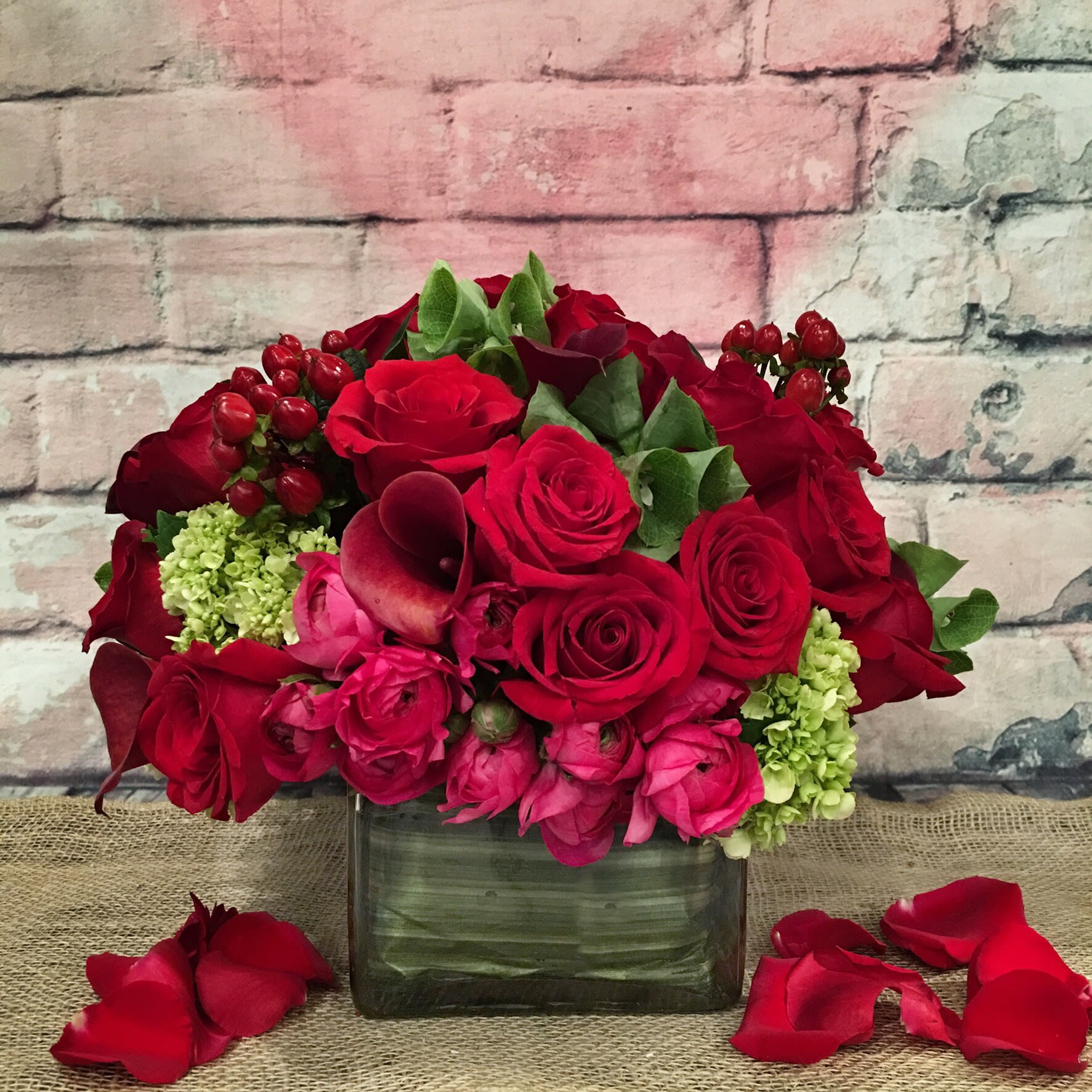 MODERN EMBRACE  - EXTRAVAGANT ROM-ANTIQUE ASSORTMENT OF RED ROSES, HOT PINK RANUNCULOS, RED CALLA LILIES, MINI GREEN HYDRANGEA, ACCENTED WITH BELLS OF IRELAND.