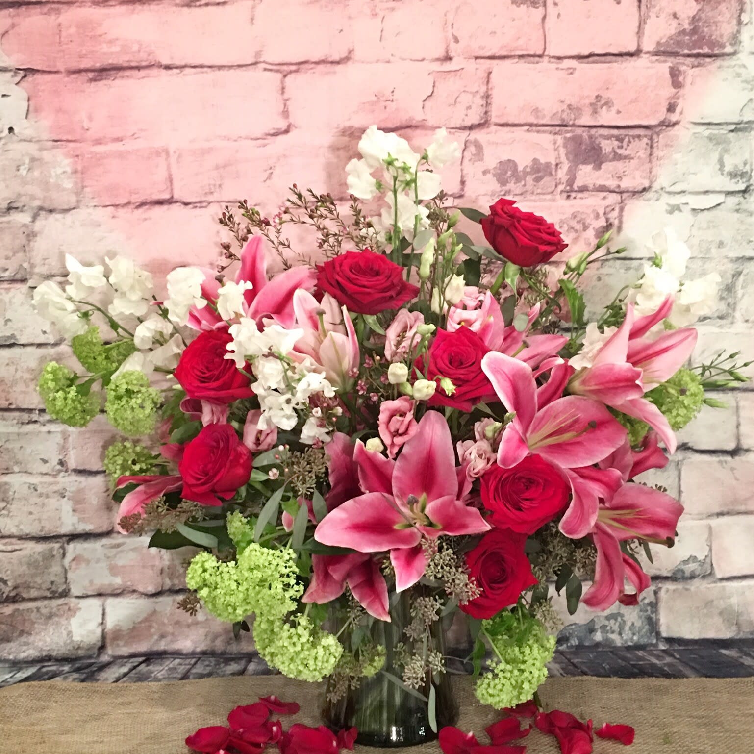 PUCKER UP - Lush arrangement compose with Hybrid Lily's, roses, sweet peas accented with snowball viburnum.  