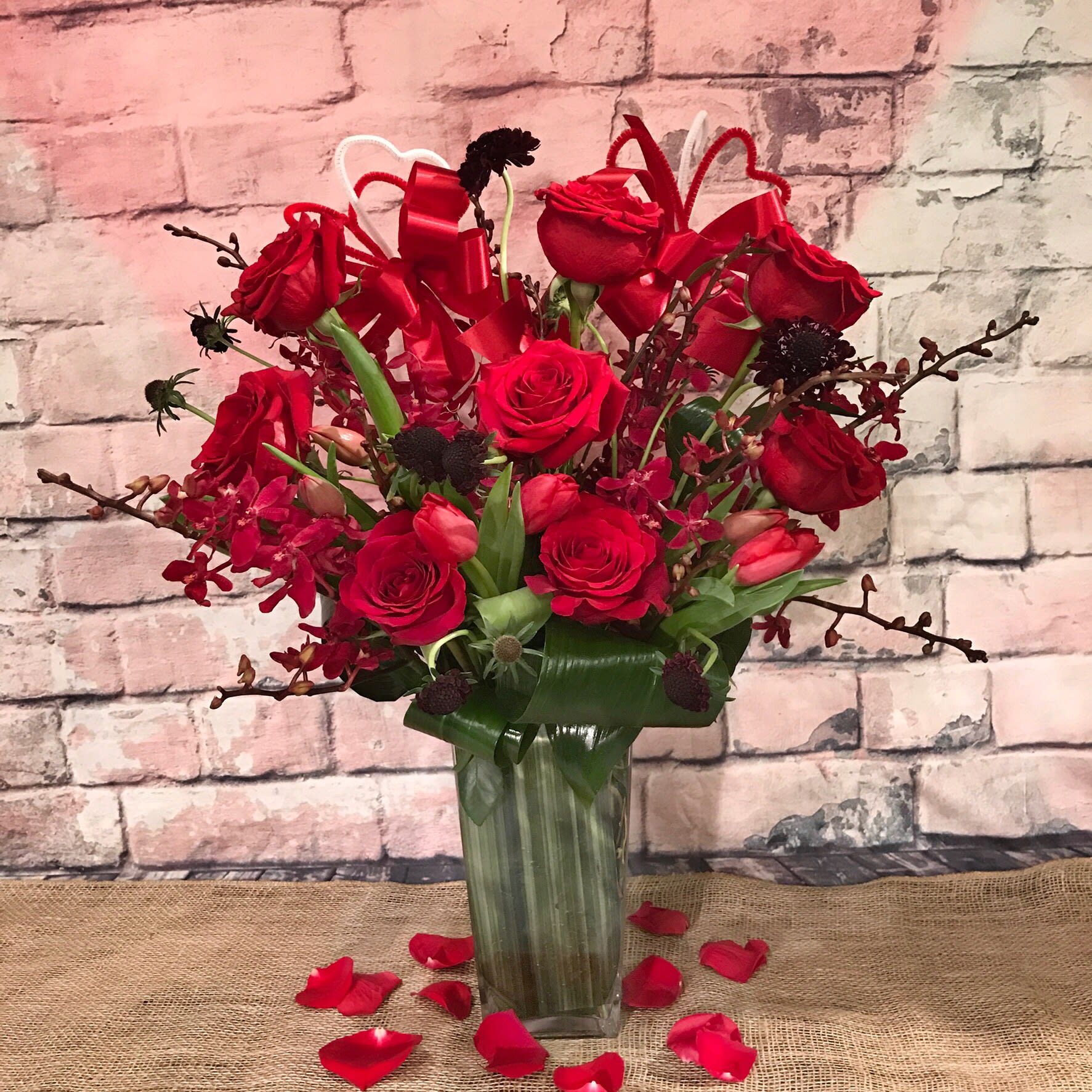 RED ROMANCE - MEDIUM HEIGHT ARRANGEMENT WITH ASSORTMENT OF RED POPPING COLORS , RED ROSES, RED AZIMA ORCHIDS, BLACK SCABIOSA  AND RED TULIPS 