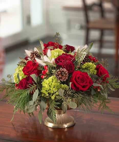 French Country Holiday Centerpiece  - In an elevated gold compote, gorgeous holiday blooms with accenting cedar, juniper, and pine. 