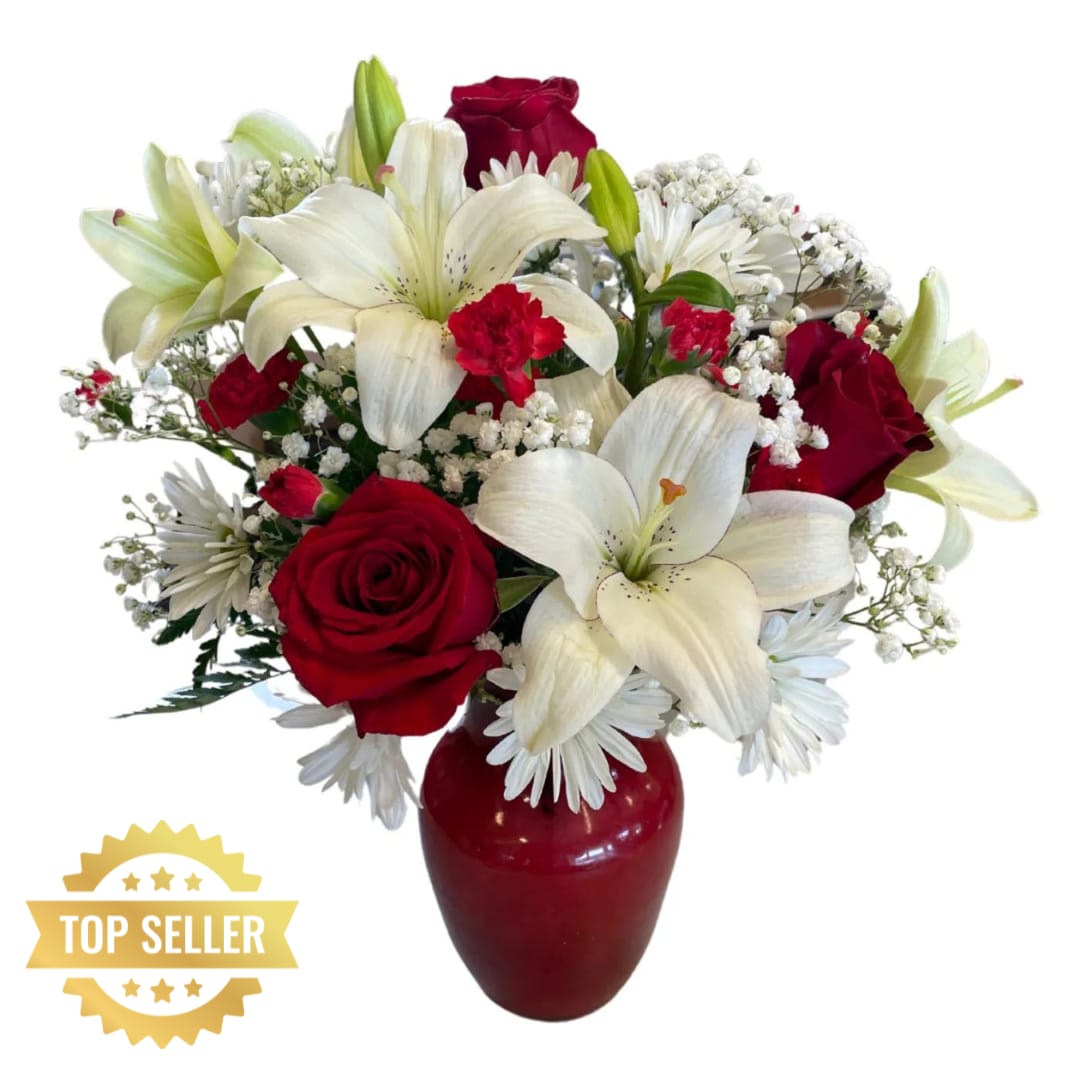 Ruby Red Love - Add some romance to the holiday season with this rich arrangement of luxurious flowers in classic winter colors. Red roses, snow white lilies and playful daisies are gathered in a ruby red vase she'll use well beyond Christmas!