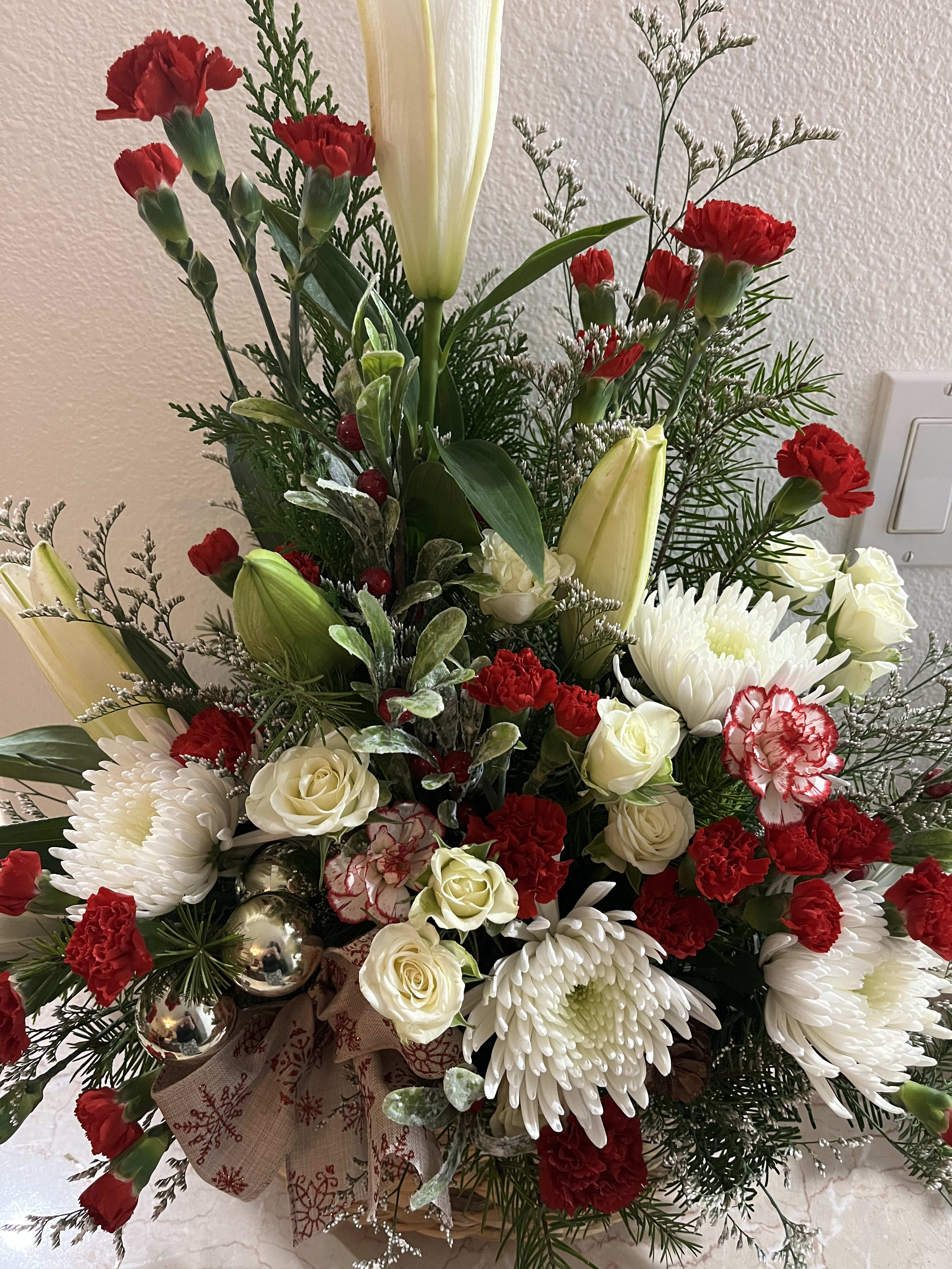 Christmas basket bouquet  - Lilies,mini carnations, mums, mixed Christmas greens, spray roses, with bulbs, and berry decor.