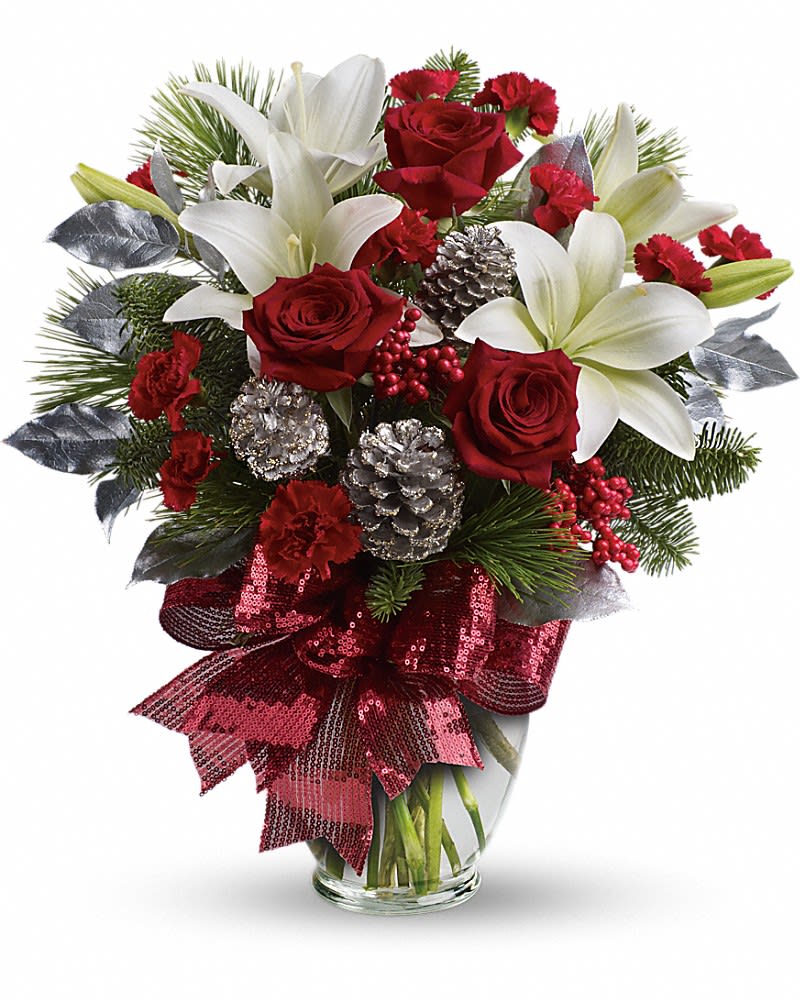 Holiday Enchantment Bouquet - Take your holiday gift-giving to new heights with this dramatic bouquet! Classic red roses snowy lilies and naturally festive berries and pine are gathered in a tall arrangement they'll long remember. A lavish arrangement of red roses white asiatic lilies red carnations noble fir white pine red berries accented with silver pinecones and leaves. Finished with a rich red ribbon this bouquet is dressed in holiday style.
