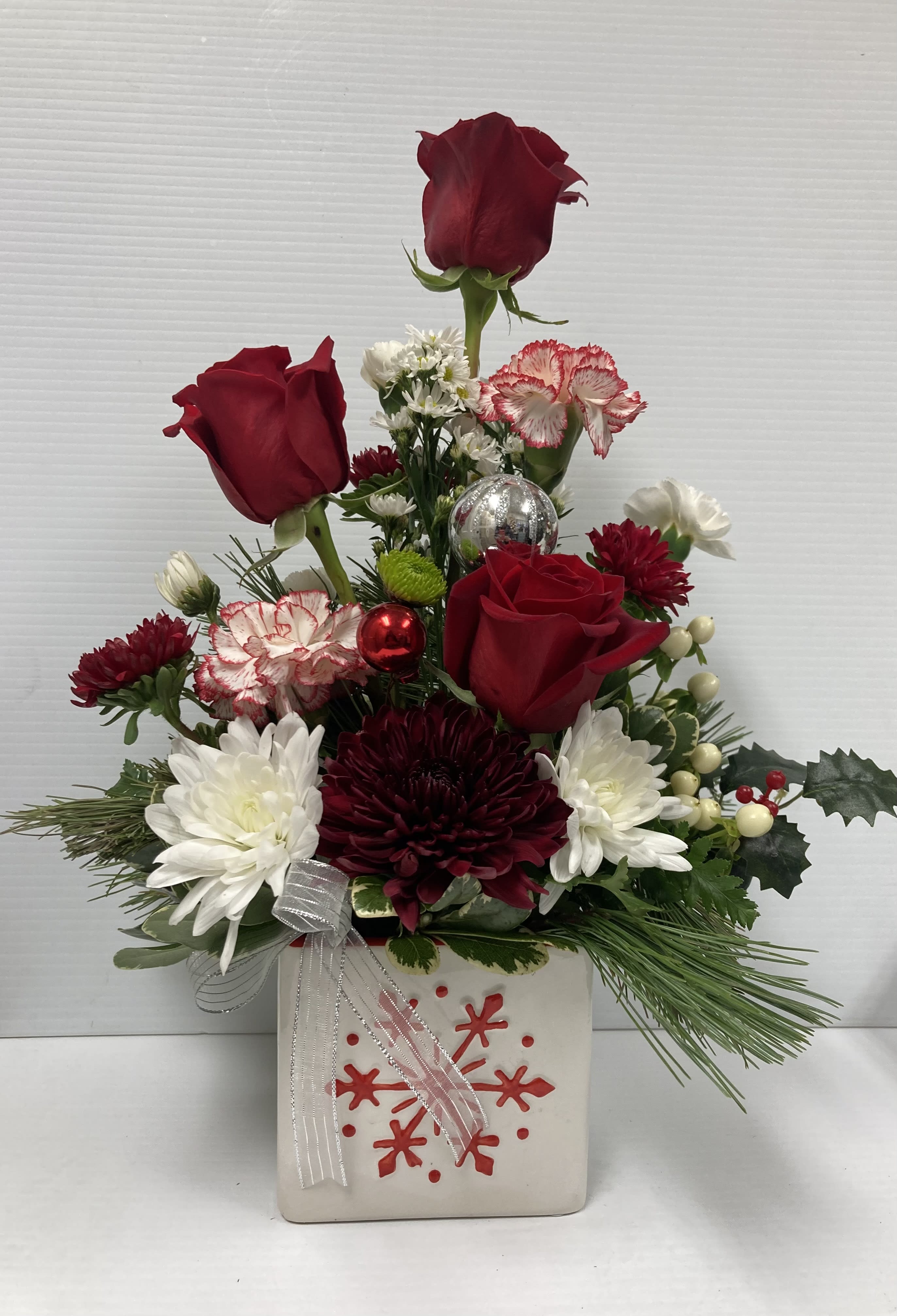 Holiday Snow Flake - Holiday arrangement in a cute snow flake glass container. Arrangement includes roses, peppermint carnations, spray roses, white carnations, mums, white daisy and greenery 
