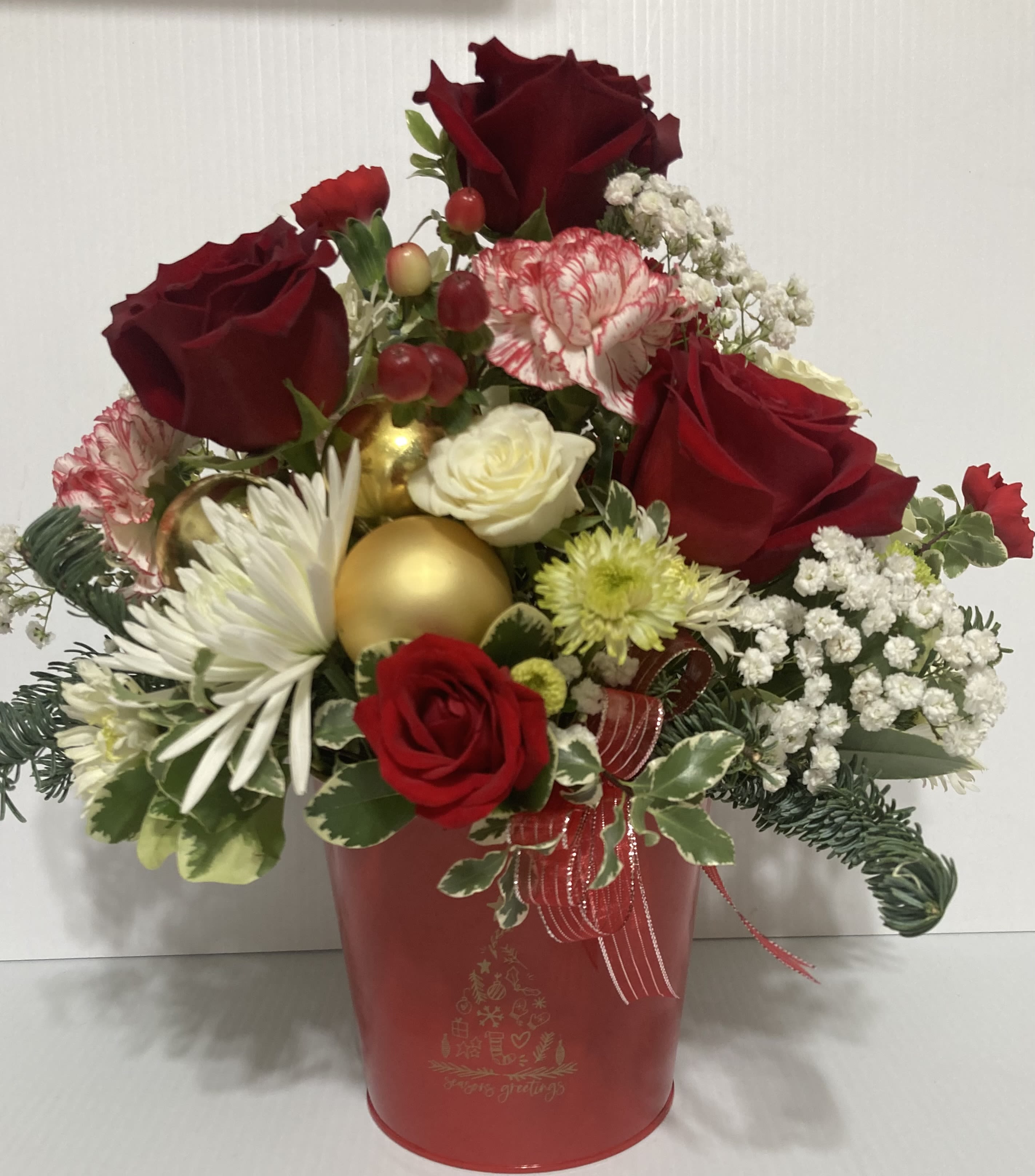 Season Greetings - Holiday arrangement in a cute red metal pot with Christmas tree on pot. Arrangement includes roses, peppermint carnations, spray roses, white carnations, mums, white daisy and greenery 