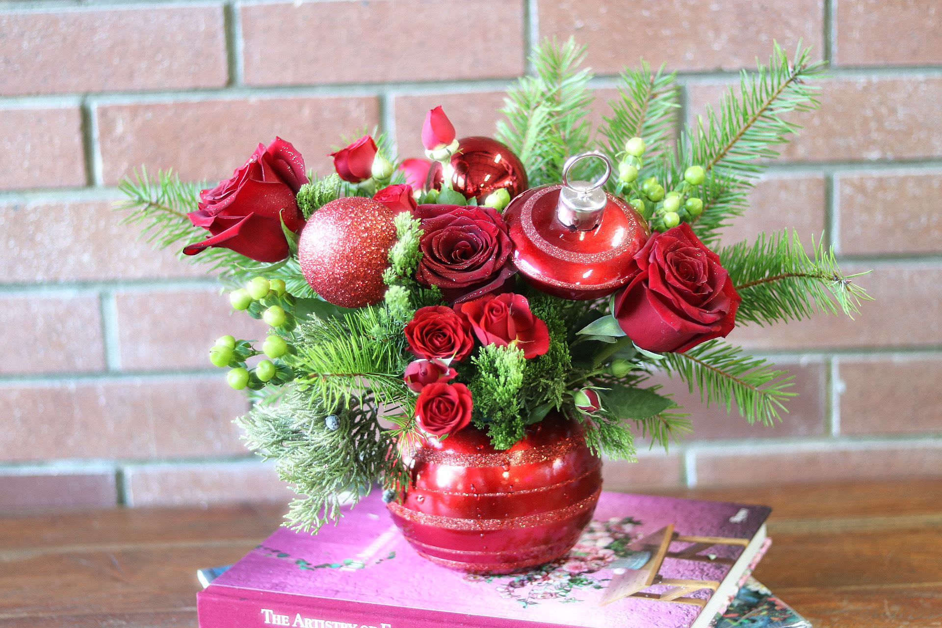 Merry &amp; Bright Ornament Bouquet  - The Merry &amp; Bright ornament bouquet is the perfect holiday centerpiece - classic red roses, green hypericum berries, red spray roses, red ornaments with fresh evergreens and green trick fresh flowers arranged in a red ornament vase with a lid - perfect keepsake for years to come.