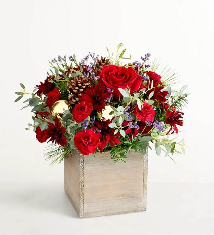 Russet Charm Flowers  - Arrangement of red roses and daisy poms, burgundy mini carnations, purple limonium, and assorted Christmas greenery, accented with pinecone picks and golden ball ornaments Artistically designed in our exclusive gray-washed wooden cube; measures 5.2"L x 5.2"H x 5.2”W Premium arrangement measures approximately 16”H x 16”W Deluxe arrangement measures approximately 15”H x 15”W Standard arrangement measures approximately 14”H x 14”W  