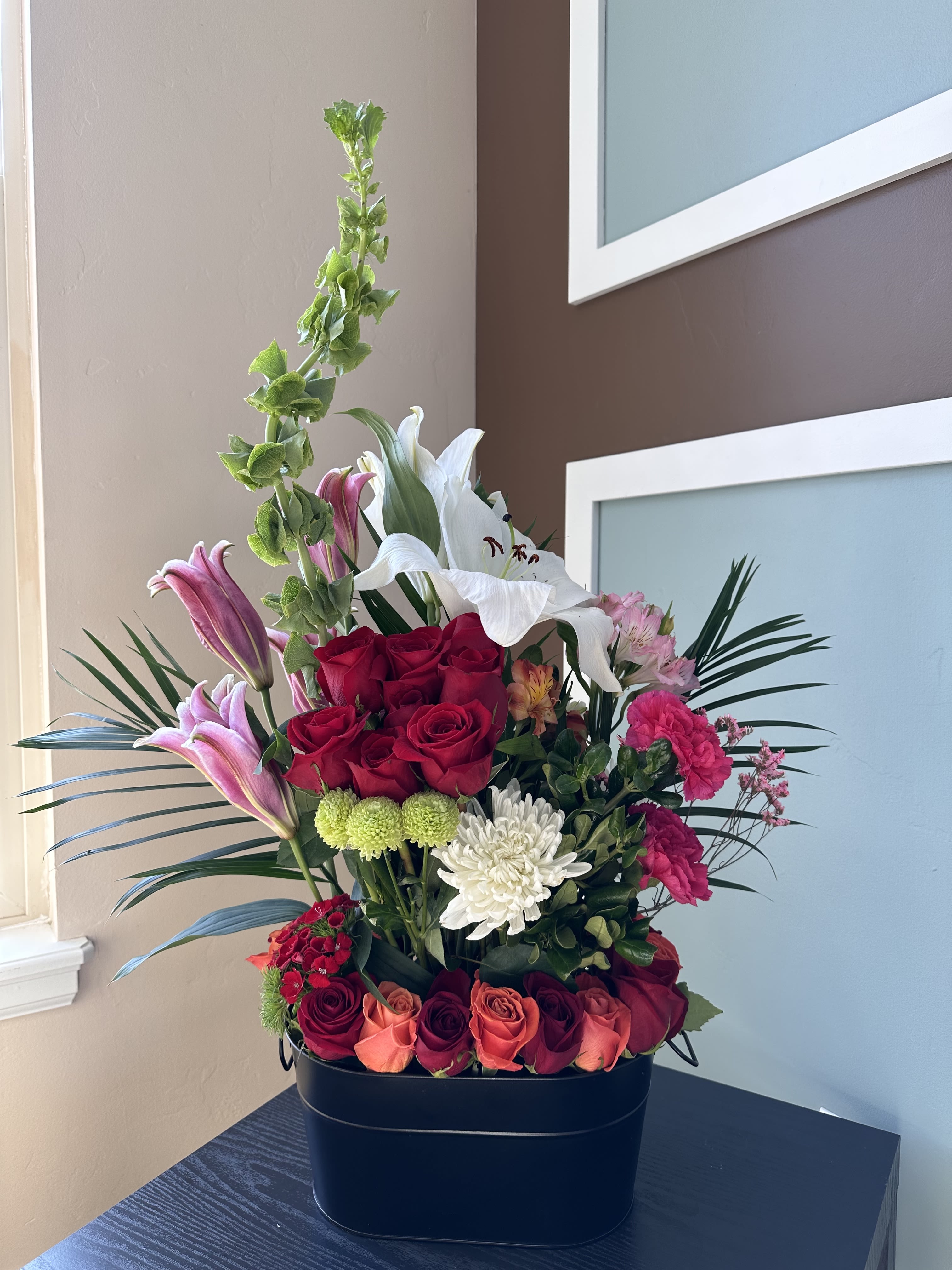 Special Floral Art - Make a lasting impression with this breathtaking floral arrangement, a true masterpiece of nature’s beauty. Featuring an exquisite blend of roses, lilies, carnations, Bells of Ireland, alstroemeria, and pompons, this piece captures a harmonious balance of color, texture, and elegance. Each bloom is carefully selected to create a stunning work of art that evokes both grace and sophistication. Perfect for any occasion, this floral creation is more than just a gift—it's a vibrant expression of beauty and emotion, designed to brighten any space.