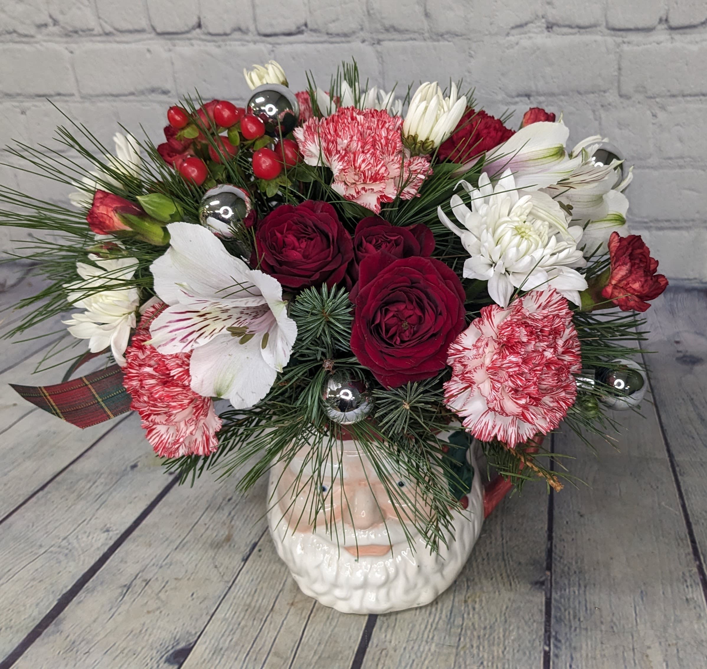 Santa Clause is Coming to Town - He's making his list and so are you. This Christmas, send a unique keepsake Santa mug bouquet to everyone on your list, whether they're naughty or nice. Bouquet is filled with a mix of candy-cane carnations, spray roses, hypericum berries, and a variety of pine. 