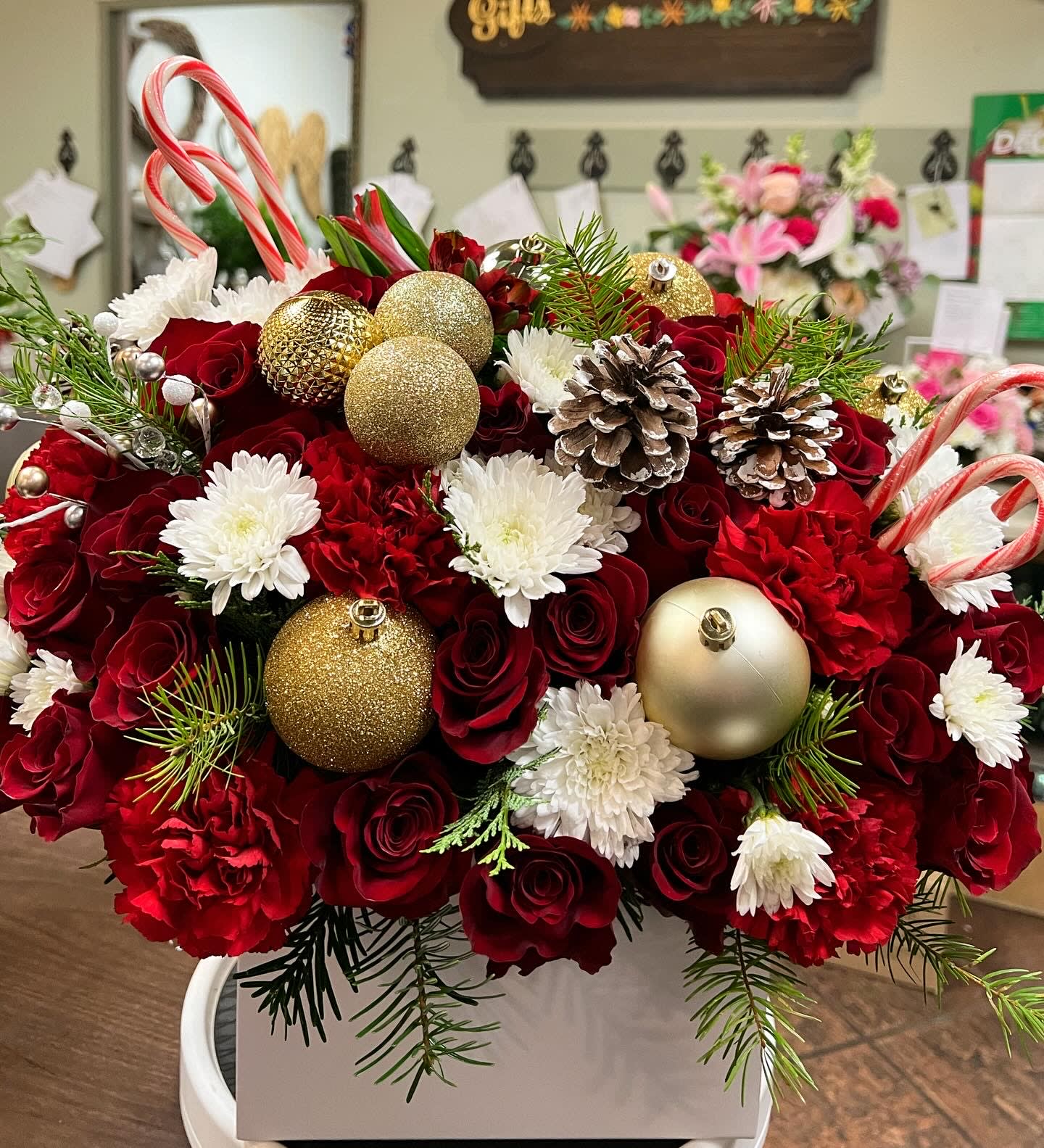 Be Merry Flower box - Christmas flower box filled with red roses, carnation, poms, alstomerias, Christmas green, candy canes, pine cones, and gold ornaments. 