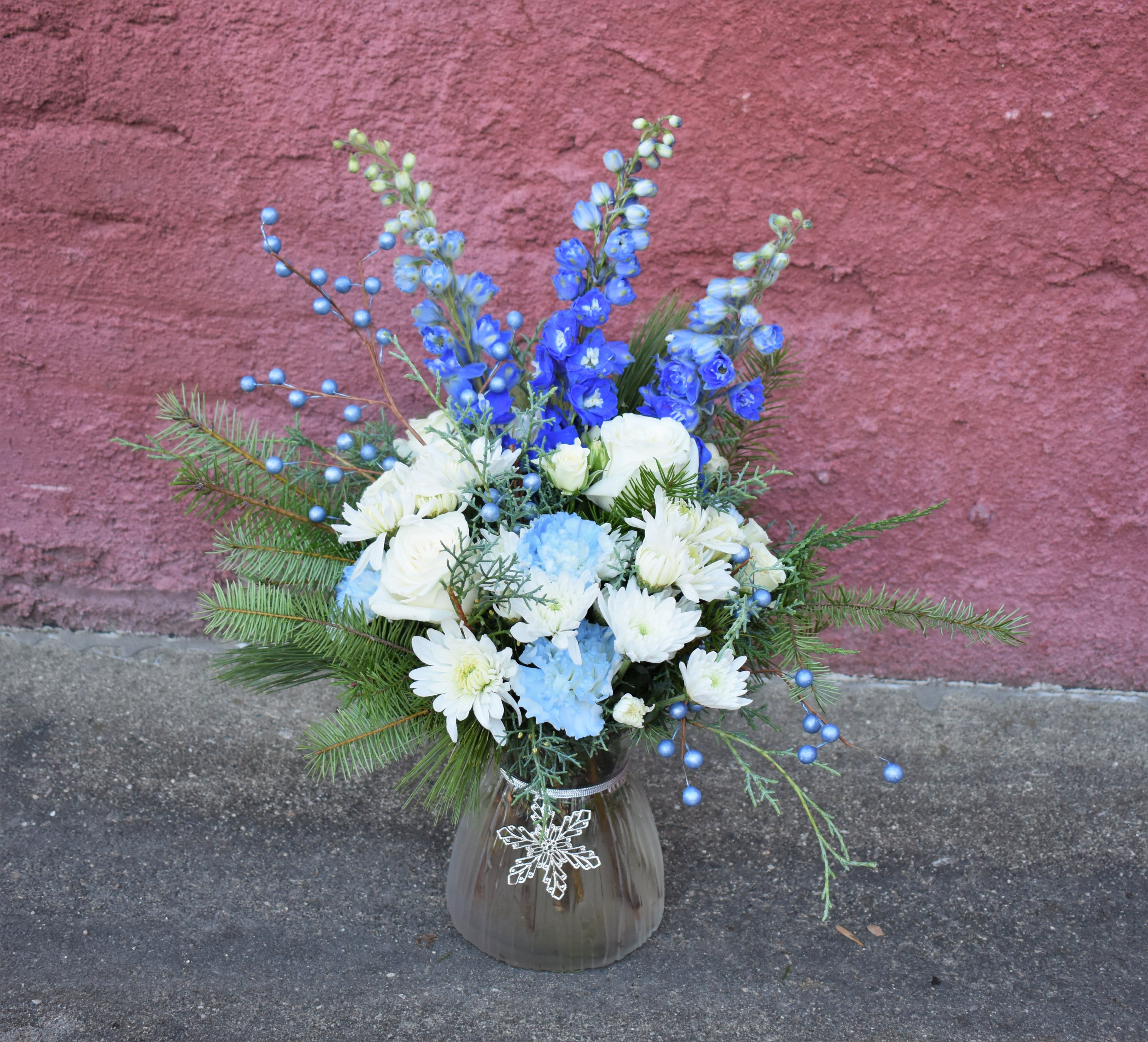 Blizzard  - Soft blues and whites make up this wintery bouquet! Blue delphinium, carnations, white mums, roses, and fresh pine are designed in a snowflake vase and accented by blue berry sprigs. The perfect wintery gift! 