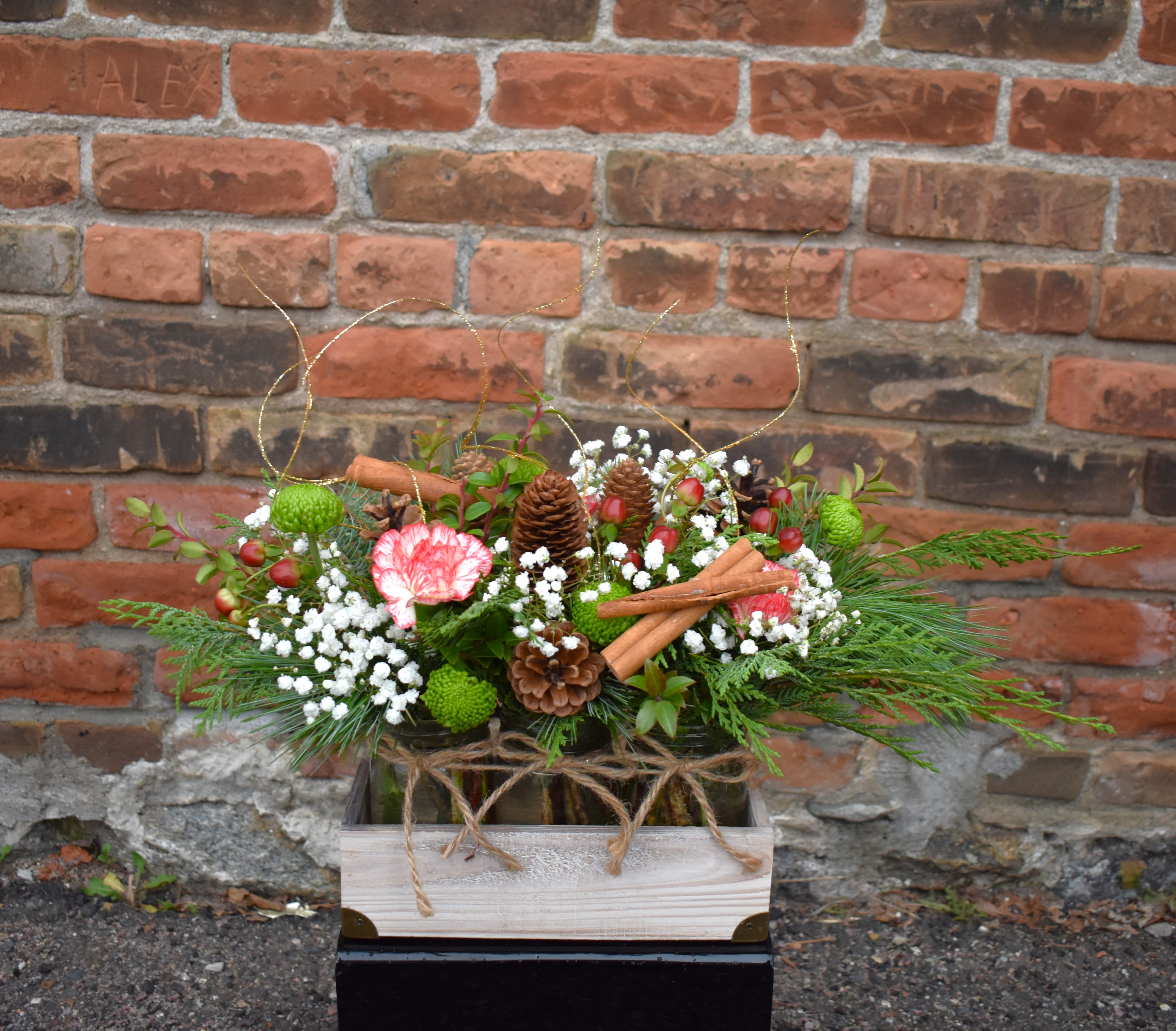 Country Christmas - Rustic and natural, this bouquet celebrate the simple joys of the season! Peppermint carnations, green button mums, red hypericum berries, white baby's-breath, and fresh pine are designed in a trip of mason jars and accented with pinecones, gold ting ting, and cinnamon sticks...the perfect bouquet for any occasion! 