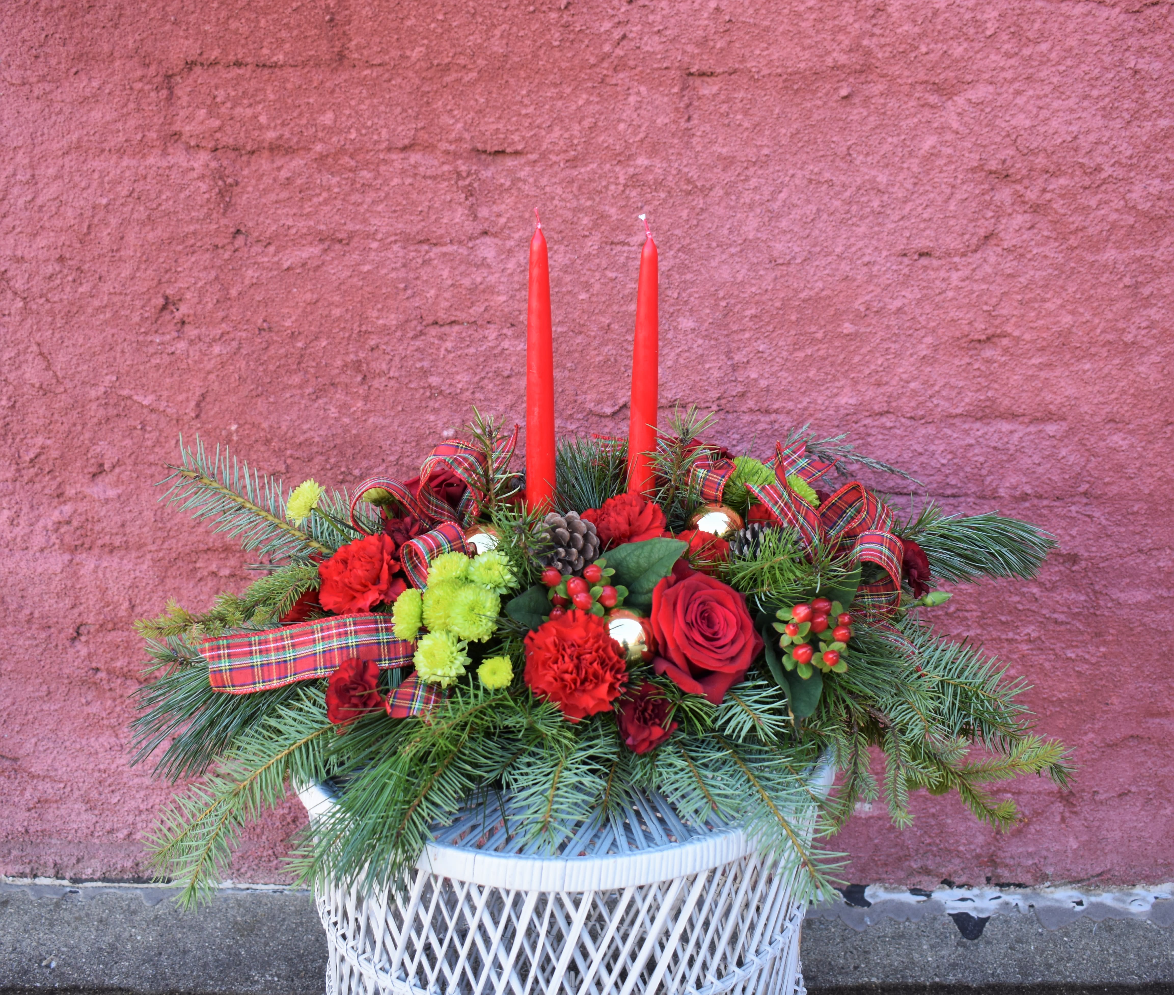 Christmas Tradition - A low centerpiece filled with roses, carnations, green button mums, pinecones, plaid ribbon, bright ornament balls, and red candles will look stunning in the center of a table on Christmas day, and is one of the best ways to celebrate all of your Christmas traditions! 