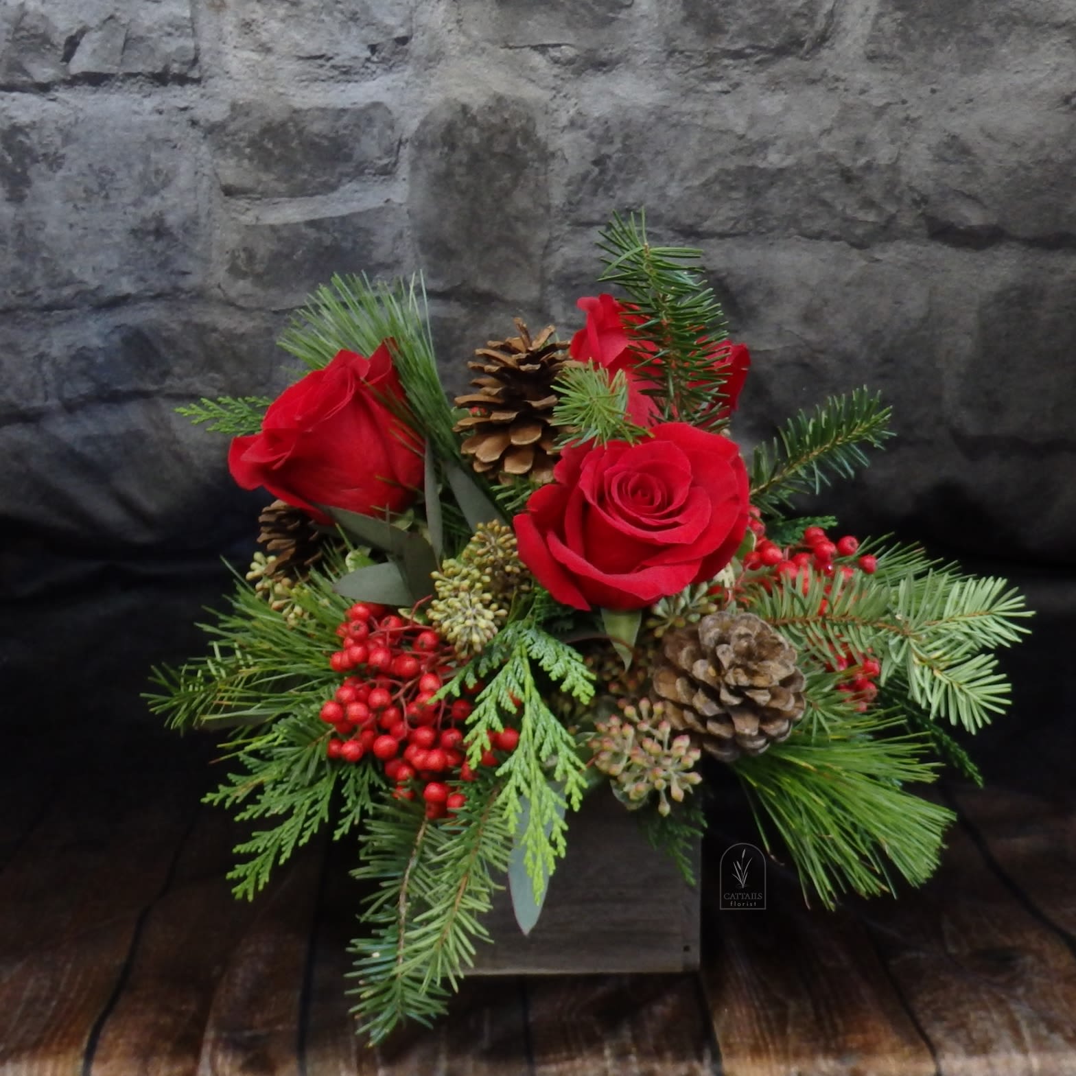 Holly Holiday - The sweetest little Christmas arrangement in a rustic wood cube. Roses, Pine cones and Berries with Christmas greens. 