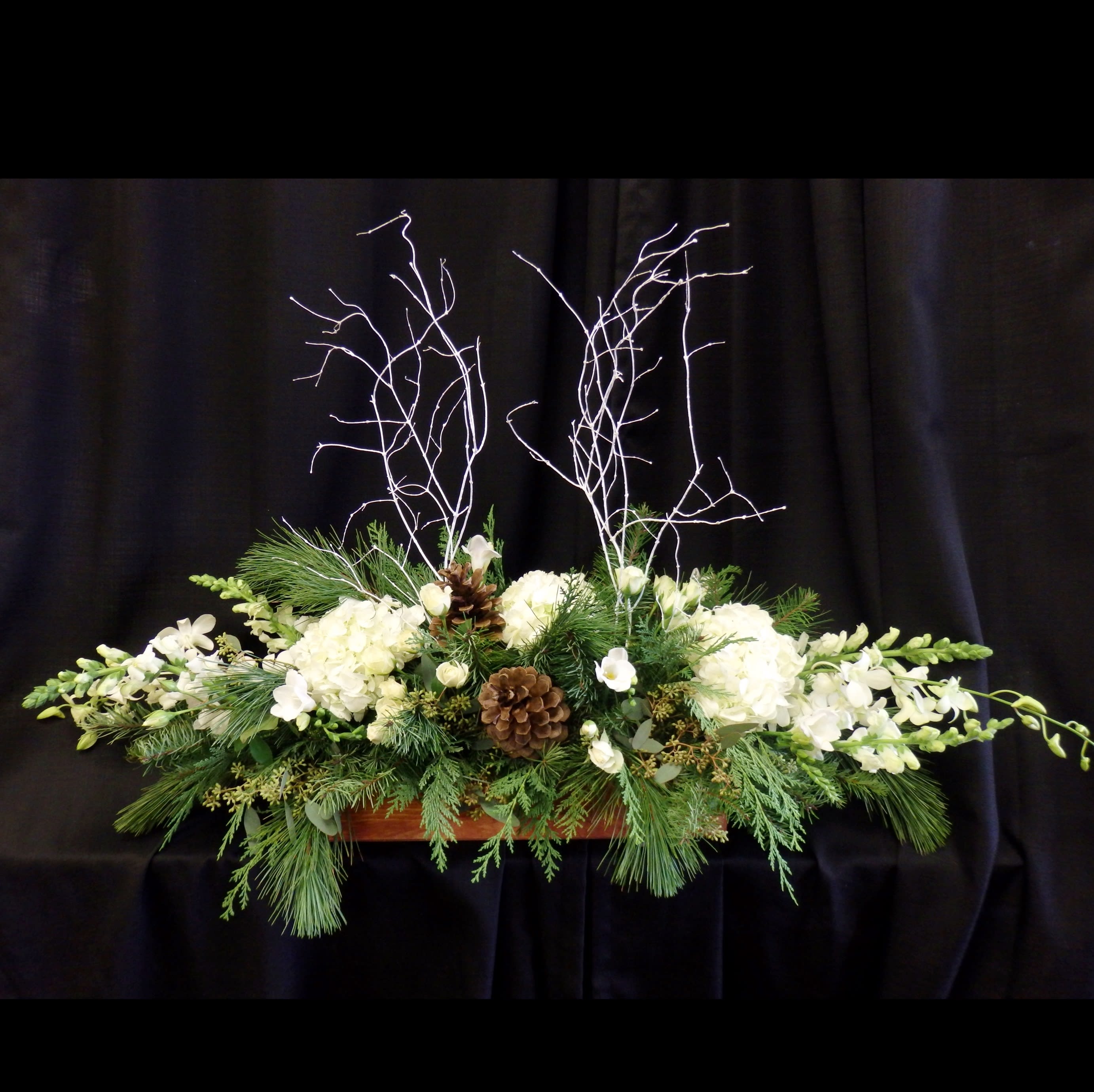 White Christmas - Natural Rustic and Earthy Holiday arrangement in a wooden box, with fragrant pine and cedar greenery and pinecones. Flowers such as Hydrangea, Roses, Spray Roses, Dendrobium Orchids, Snap Dragons, and White Branches.  
